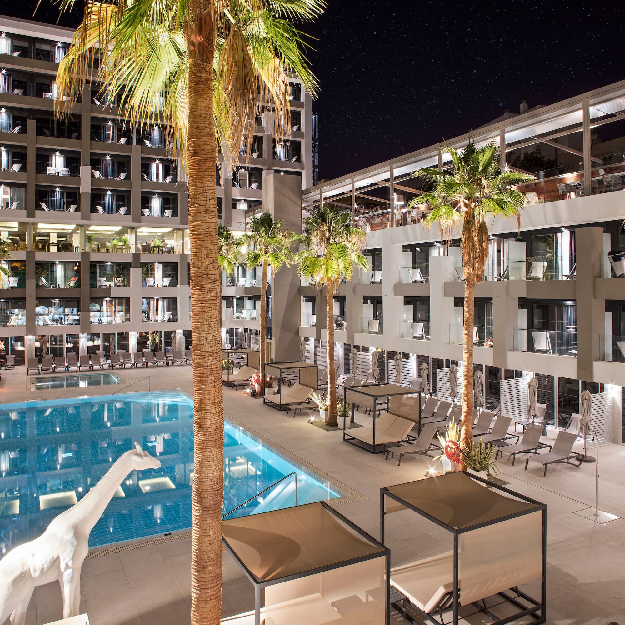 a swimming pool and palm trees in front of a building