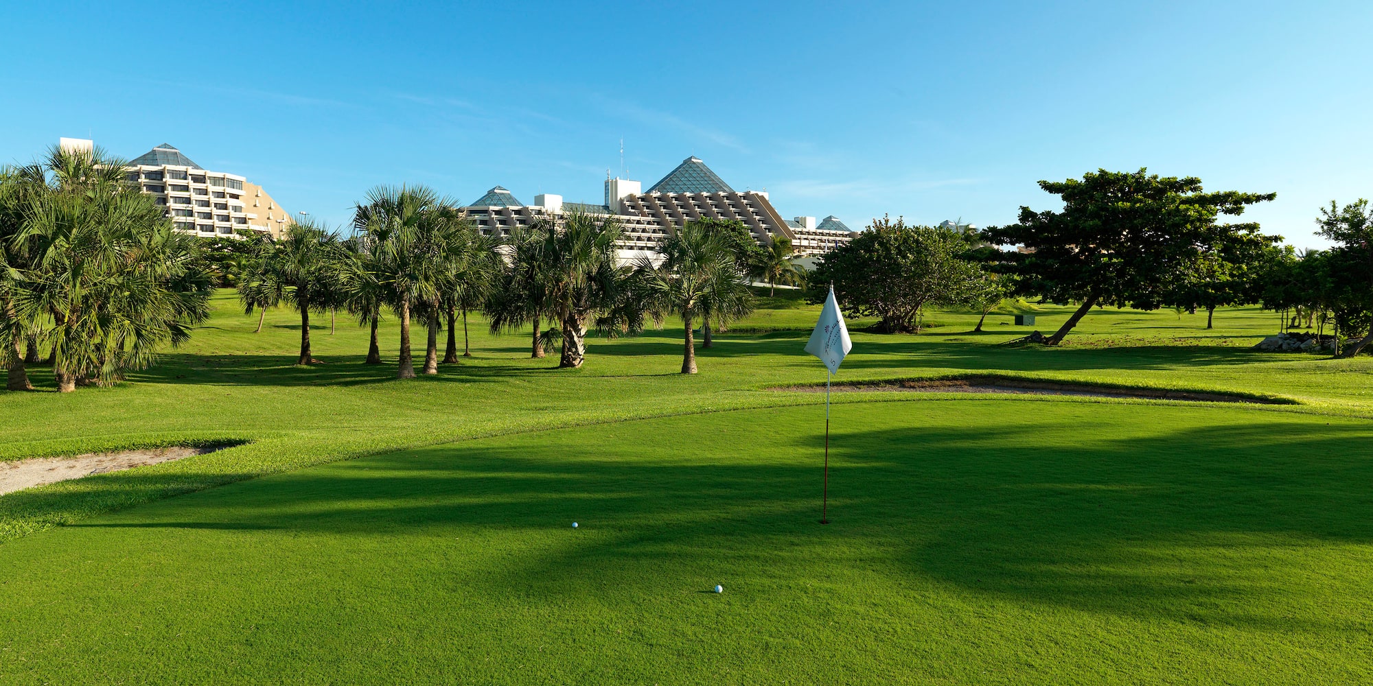a golf course with trees and a building in the background