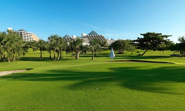 a golf course with trees and a building in the background