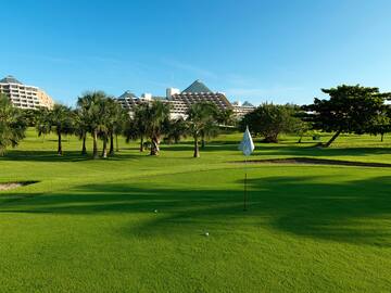 a golf course with trees and a building in the background