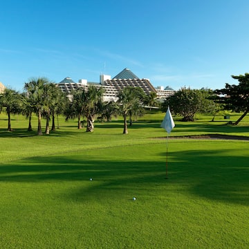 a golf course with trees and a building in the background