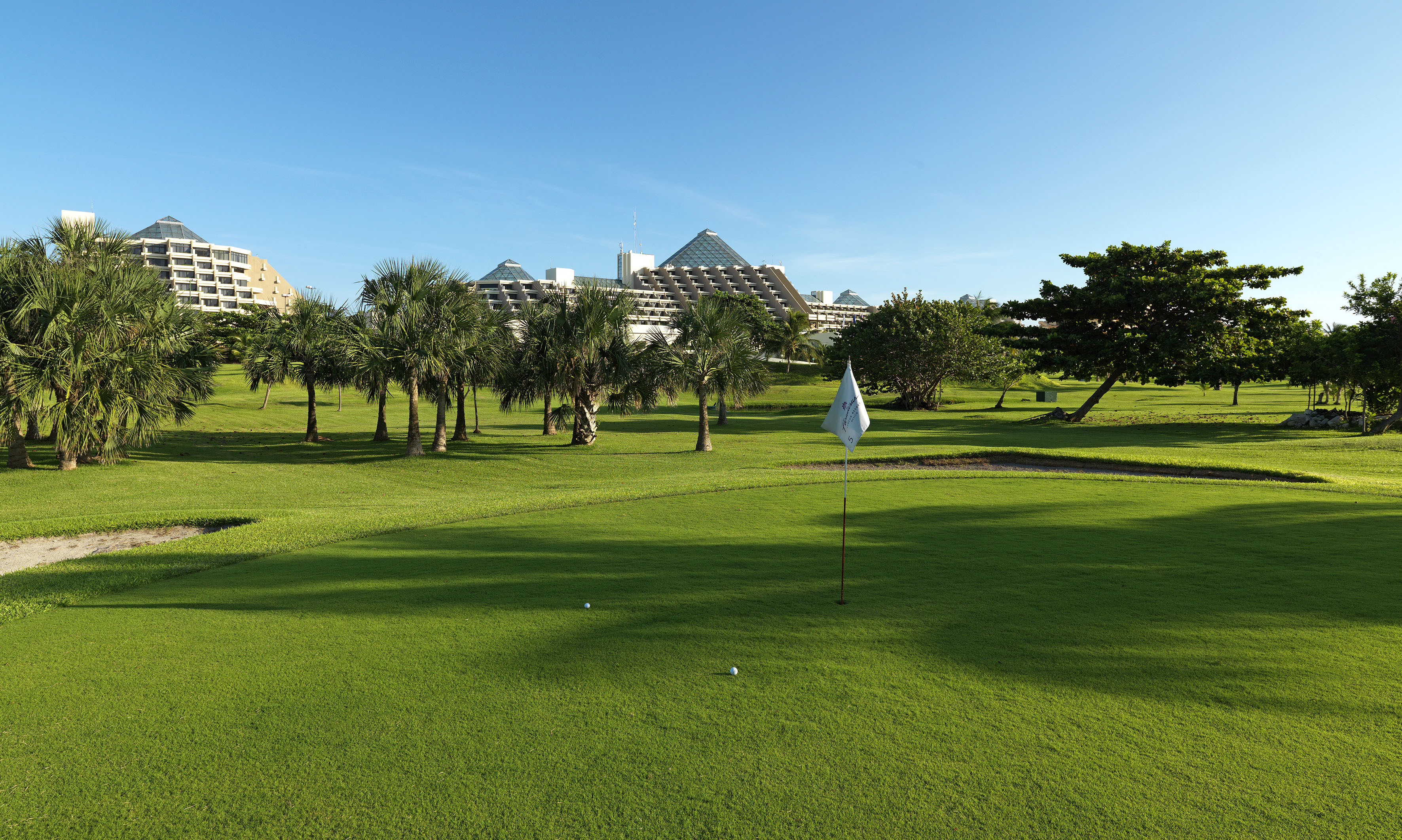 a golf course with trees and a building in the background