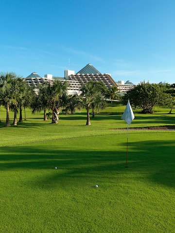 a golf course with trees and a building in the background