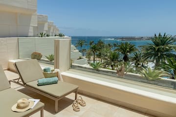 a lounge chair on a balcony overlooking a body of water