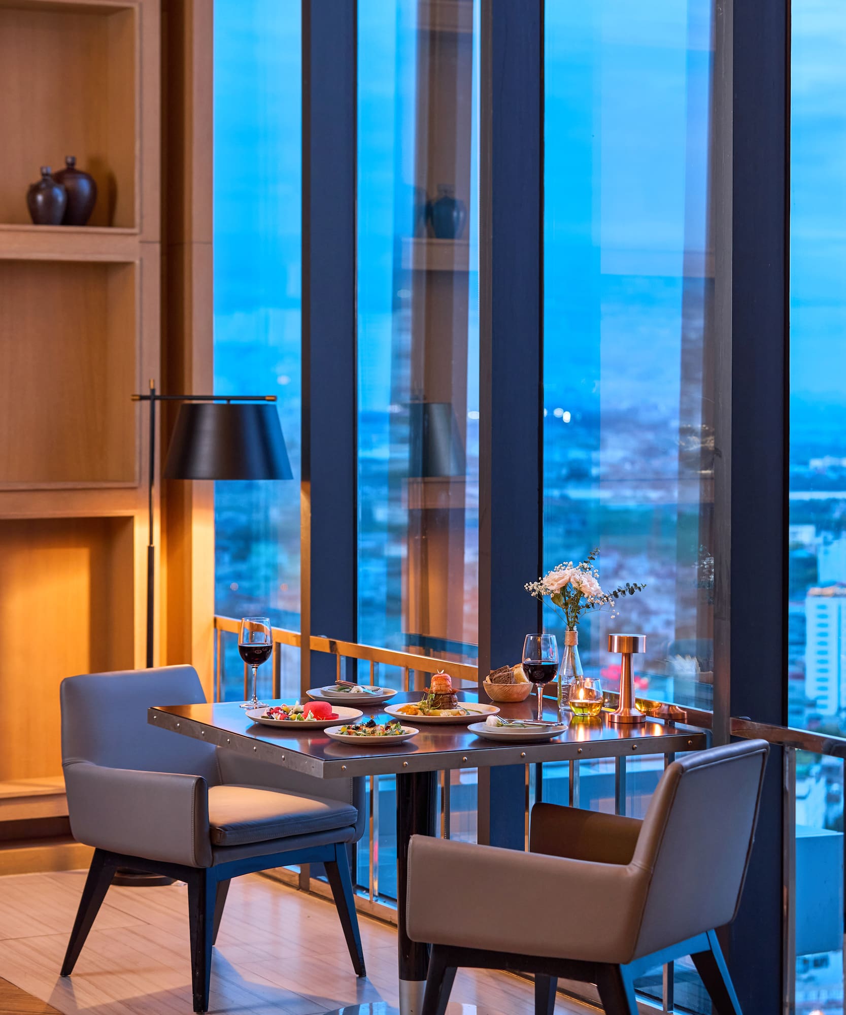 a table with food on it and chairs in front of a window