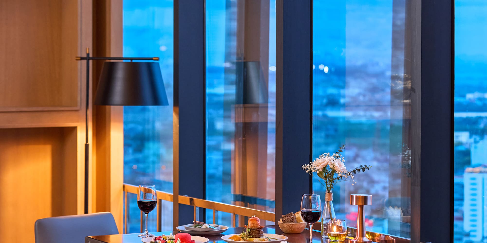 a table with food on it and chairs in front of a window