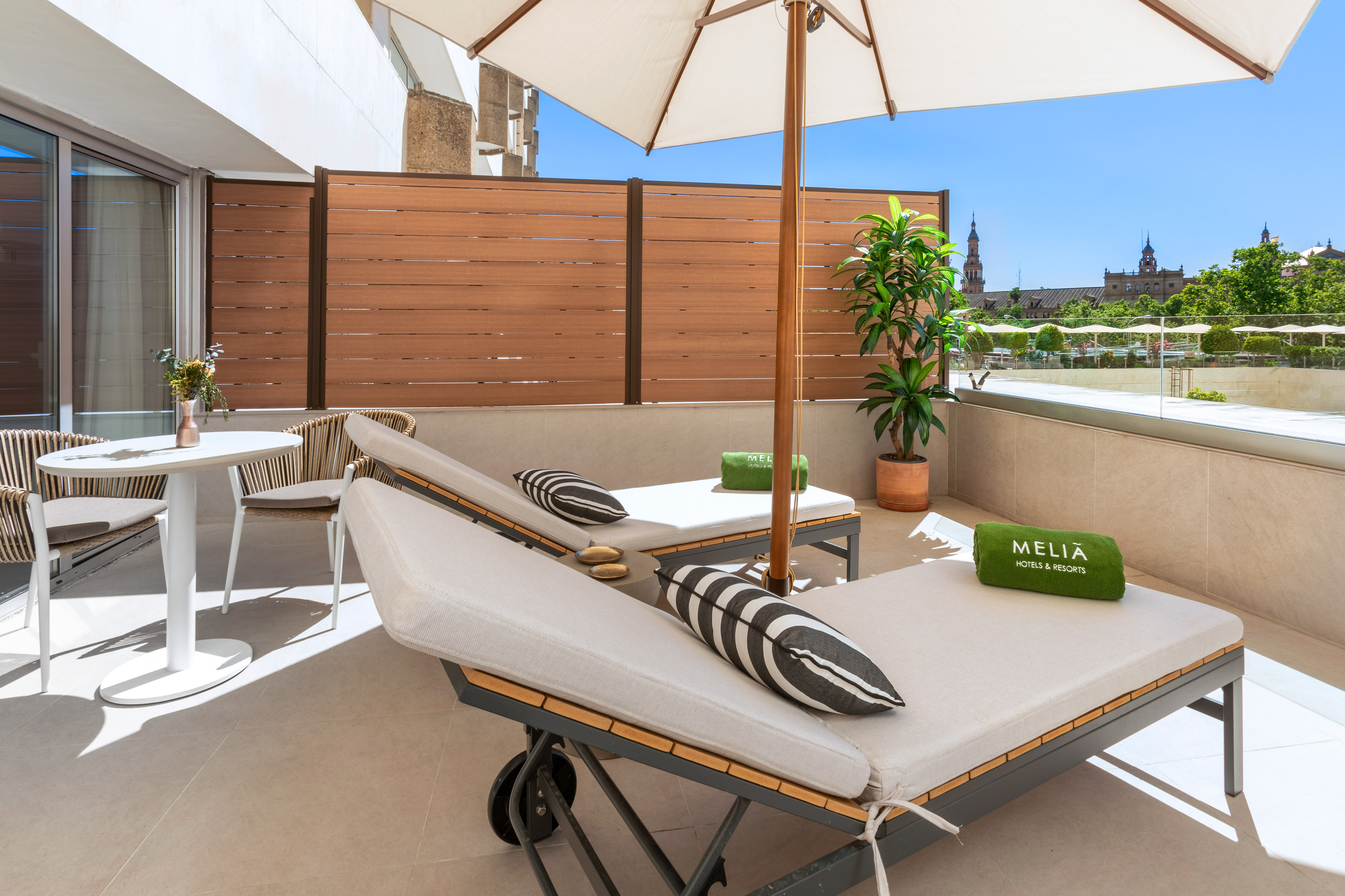 Meliã hotel balcony with lounge chairs, umbrella, and city skyline view.
