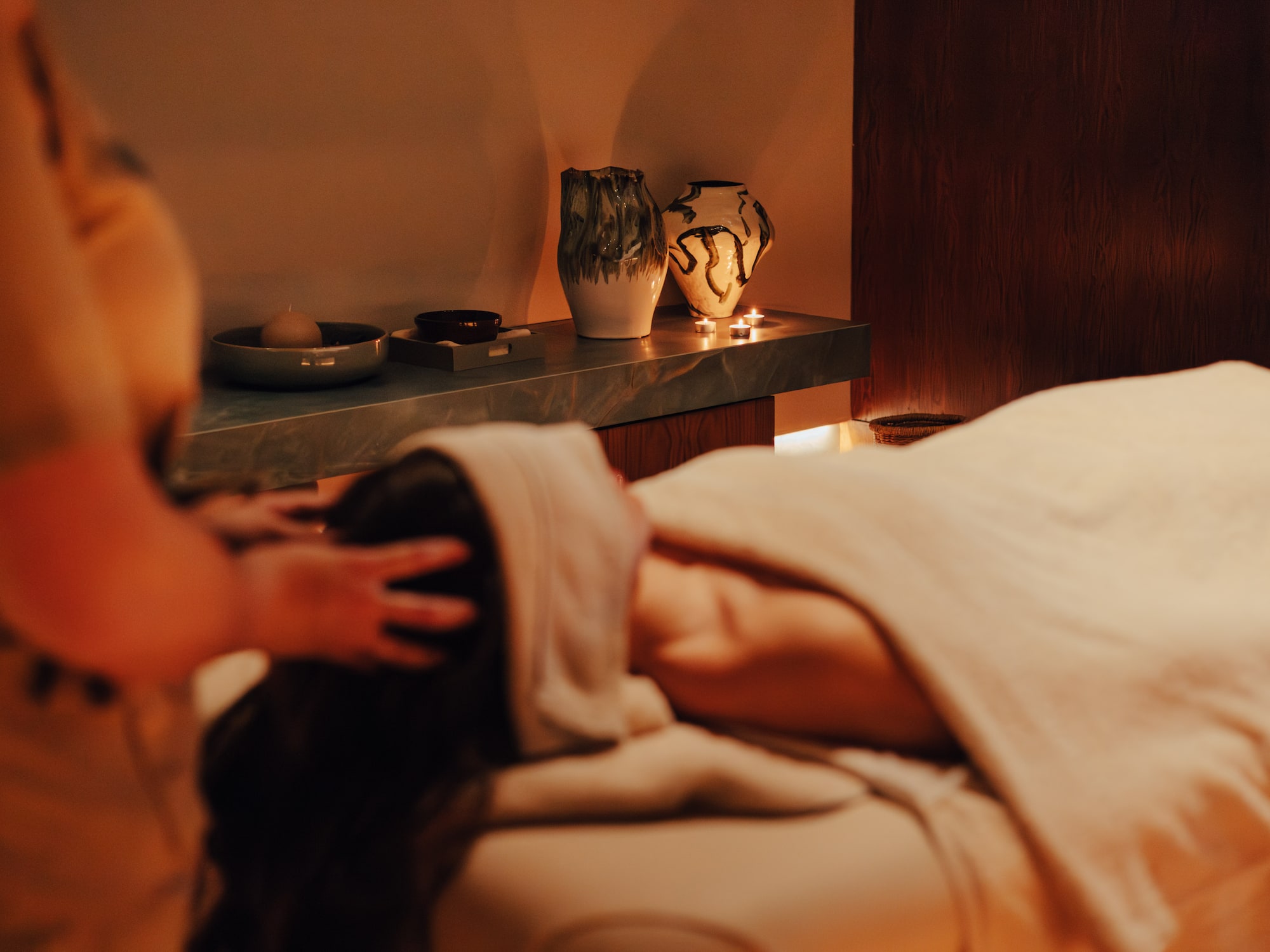 Client receiving relaxing head massage at a warm spa with ambient light.