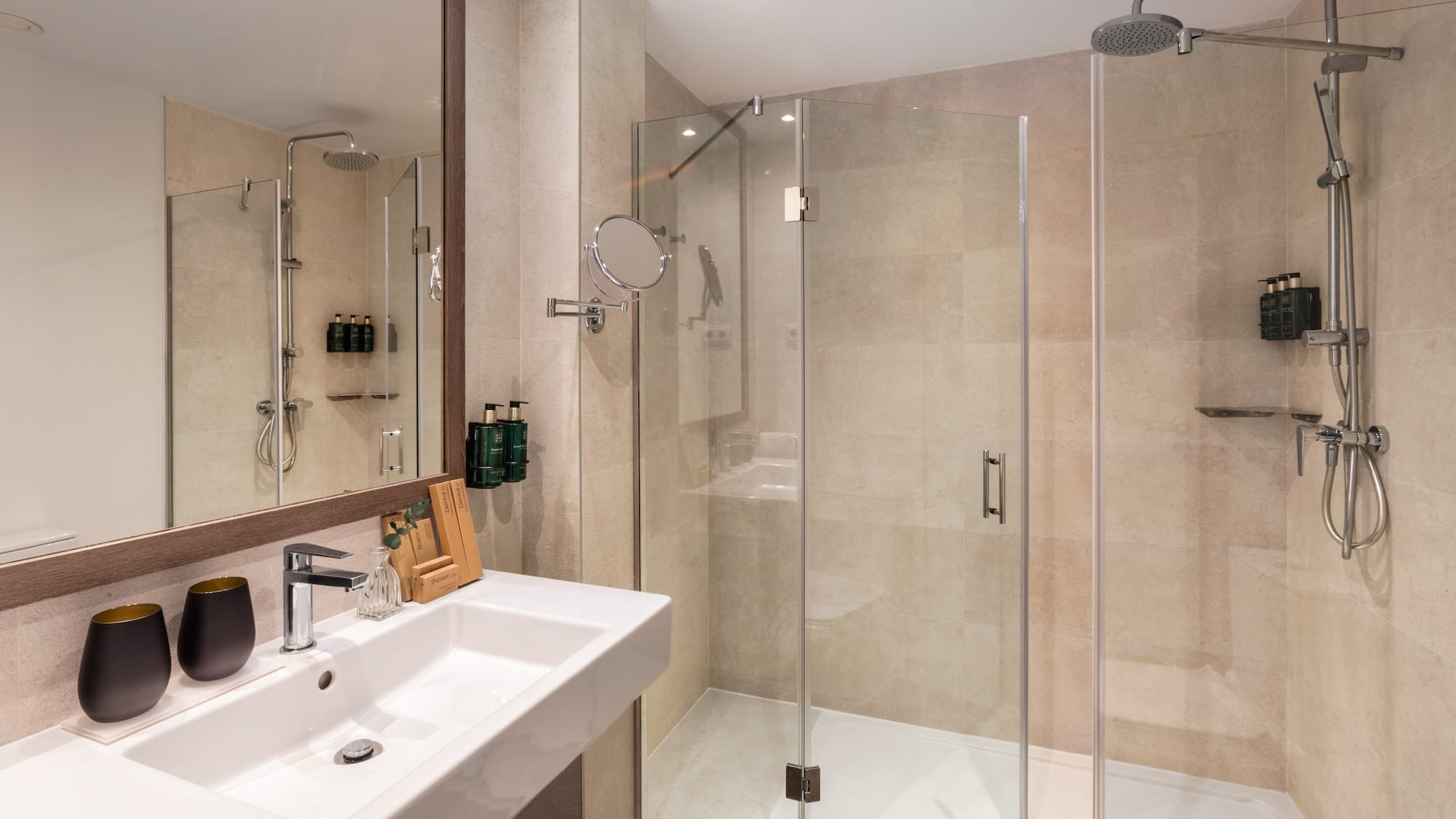 Modern hotel bathroom with walk-in shower, vanity sink, and mirror.