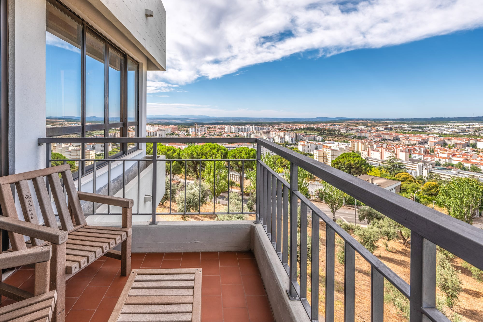 a balcony with a view of a city and a blue sky
