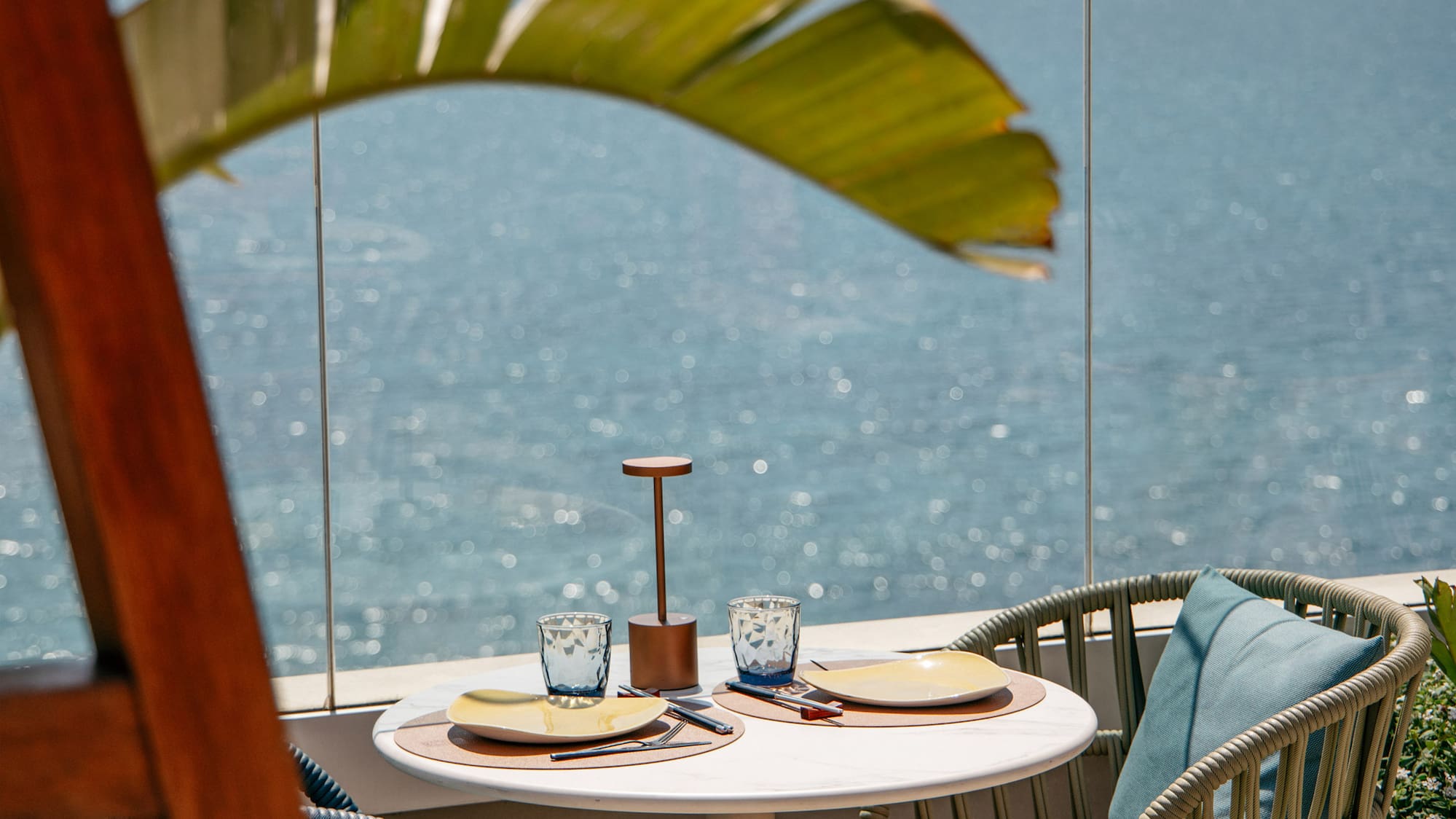 a table with chairs and a glass fence overlooking the ocean