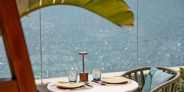 a table with chairs and a glass fence overlooking the ocean