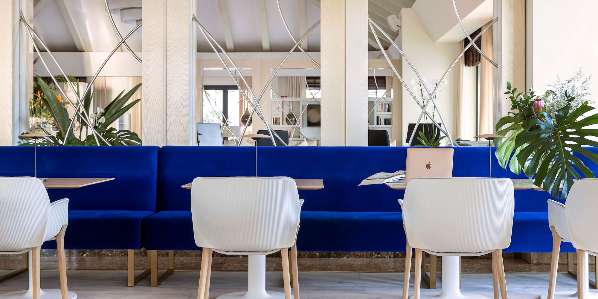 a blue couch and white chairs in a room with mirrors