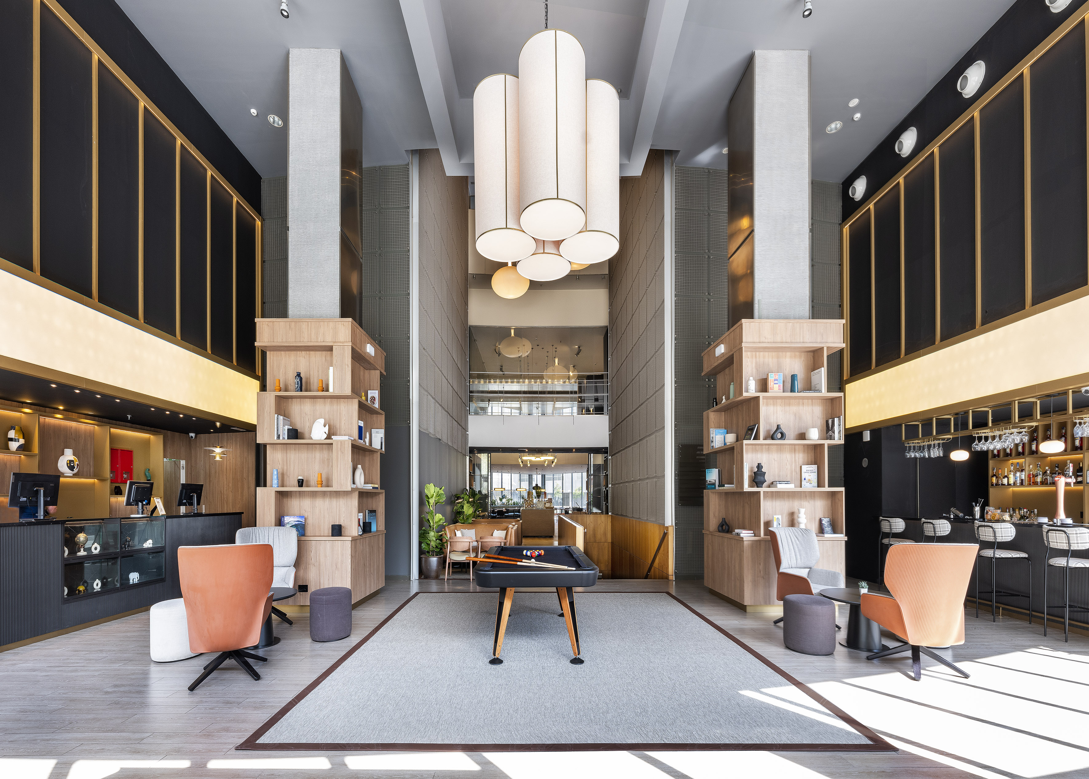 Modern hotel lobby lounge with billiards table, reception, and bar.