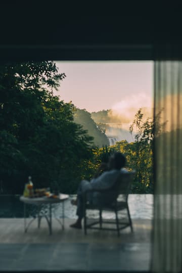 a person sitting in a chair outside with a waterfall in the background
