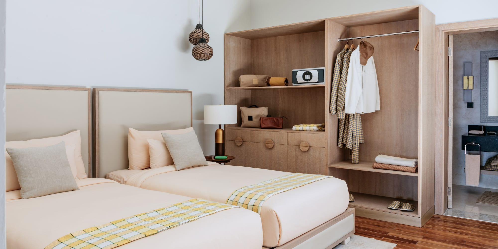Cozy hotel room with twin beds, wooden wardrobe, and bright plaid throws.