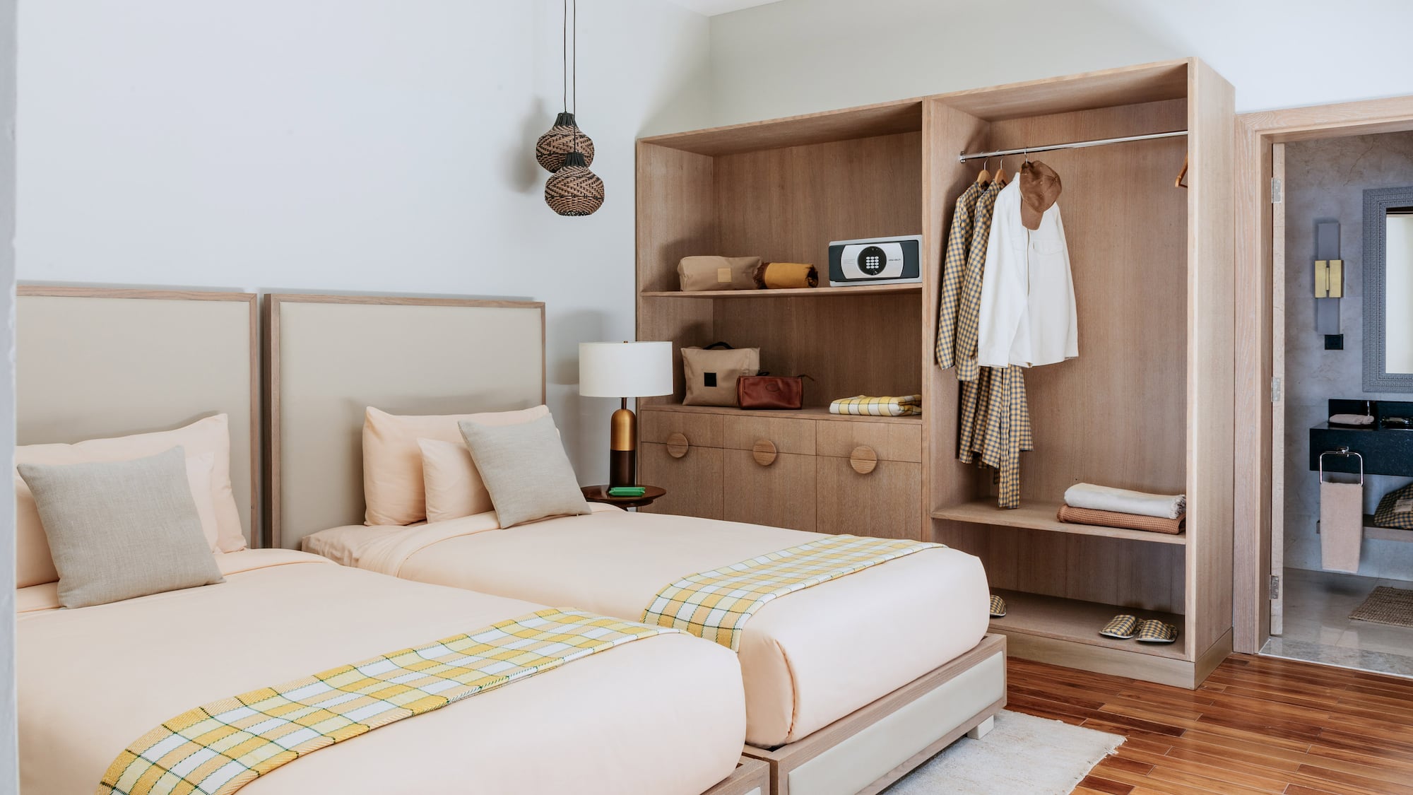 Cozy hotel room with twin beds, wooden wardrobe, and bright plaid throws.