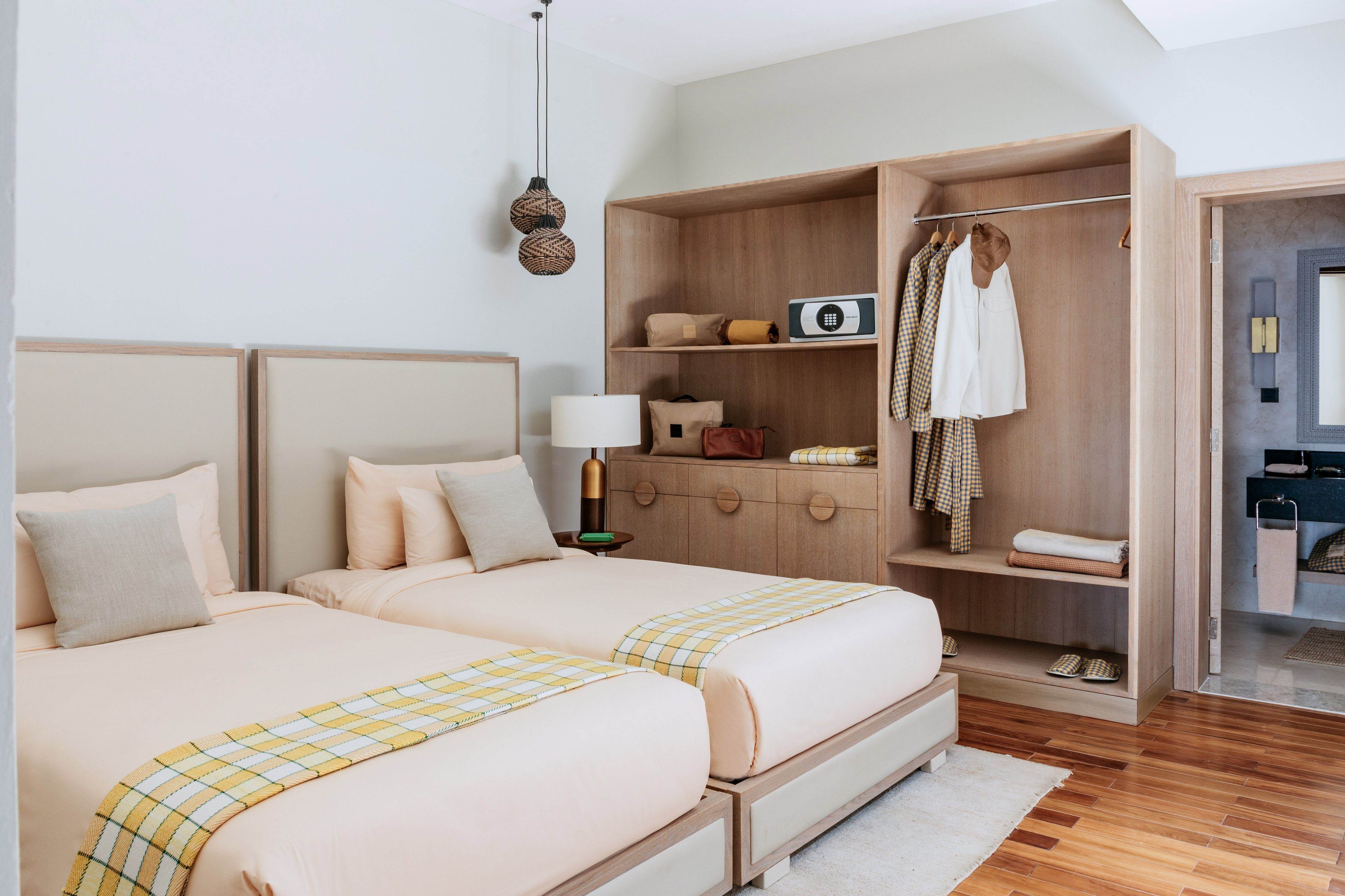 Cozy hotel room with twin beds, wooden wardrobe, and bright plaid throws.
