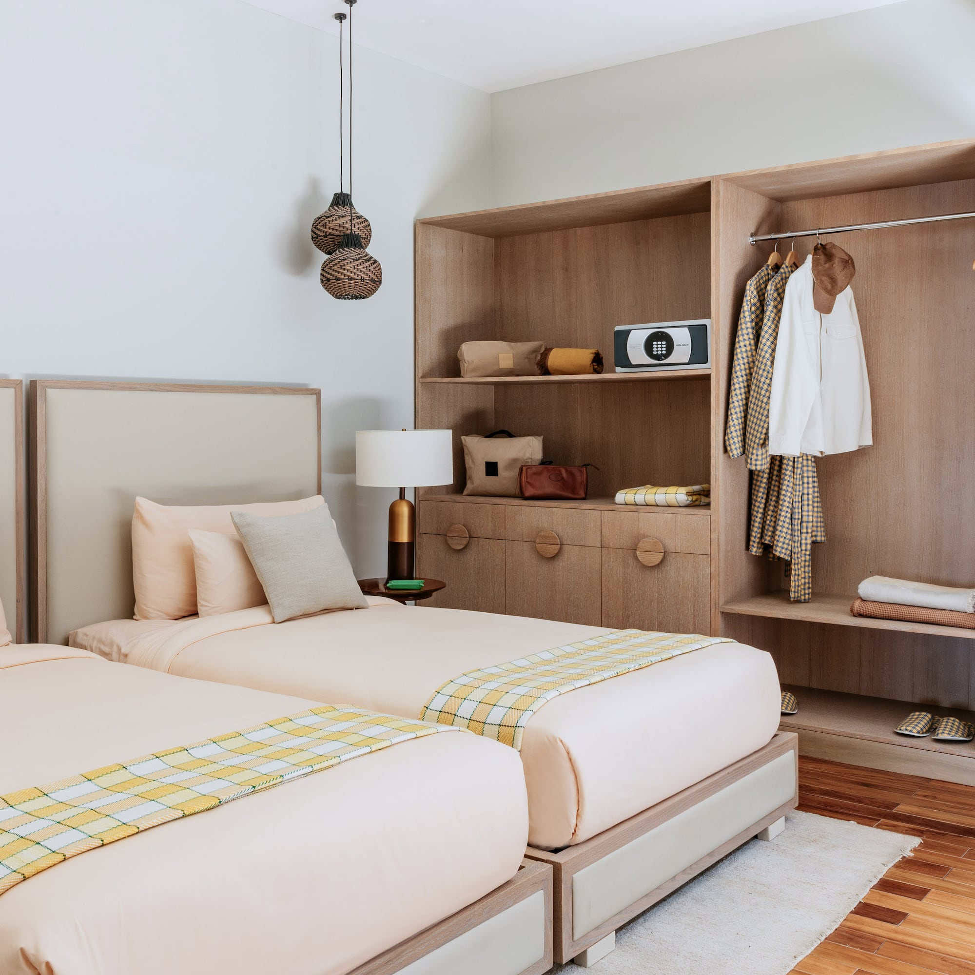 Cozy hotel room with twin beds, wooden wardrobe, and bright plaid throws.