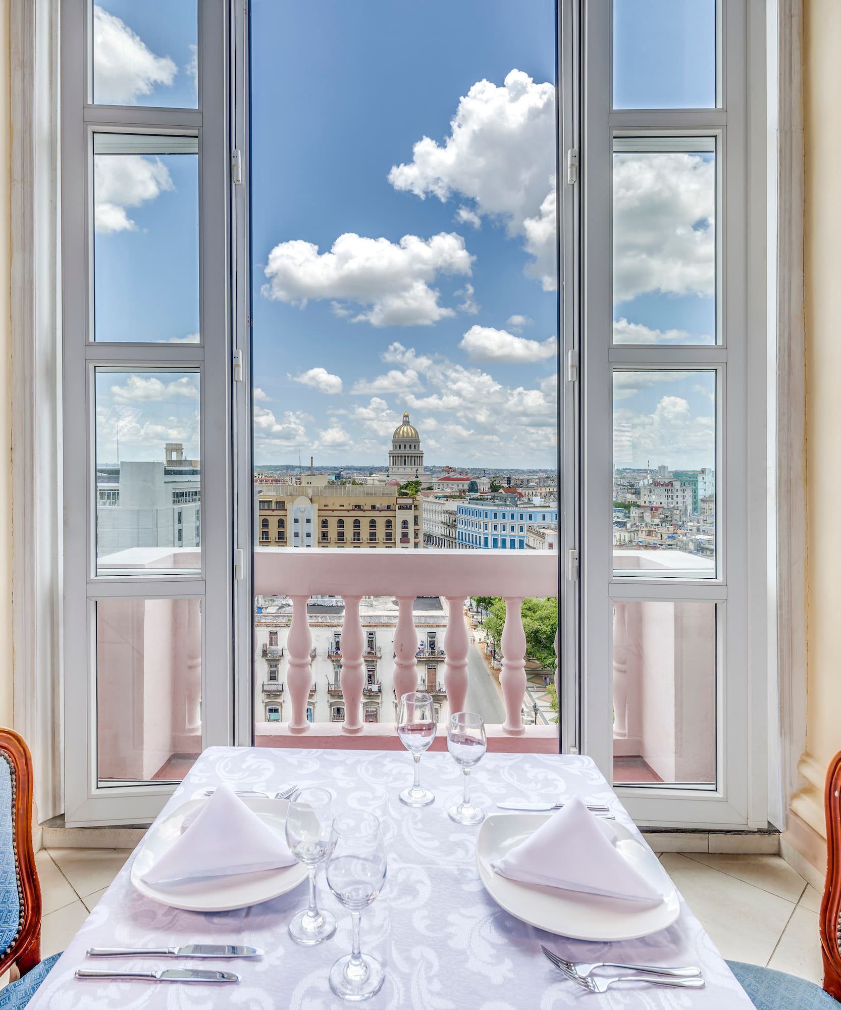 a table set for two with chairs and a balcony overlooking a city