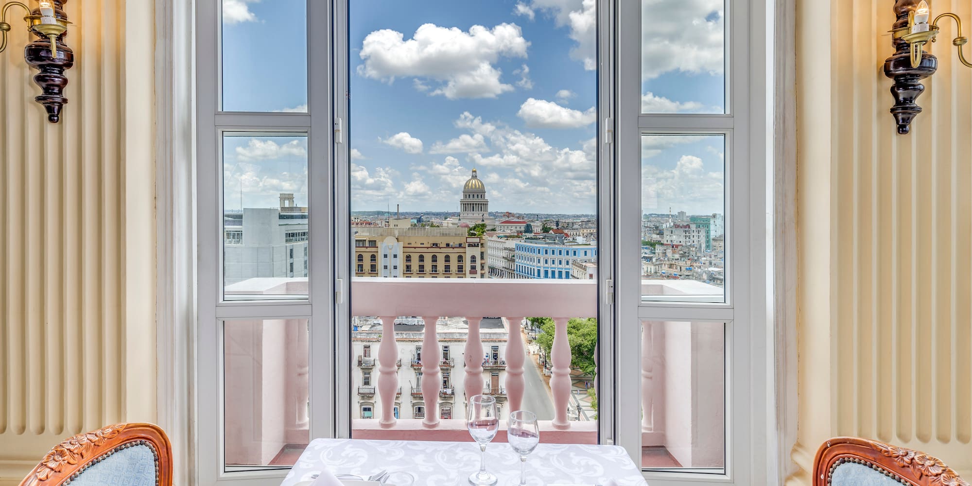 a table set for two with chairs and a balcony overlooking a city