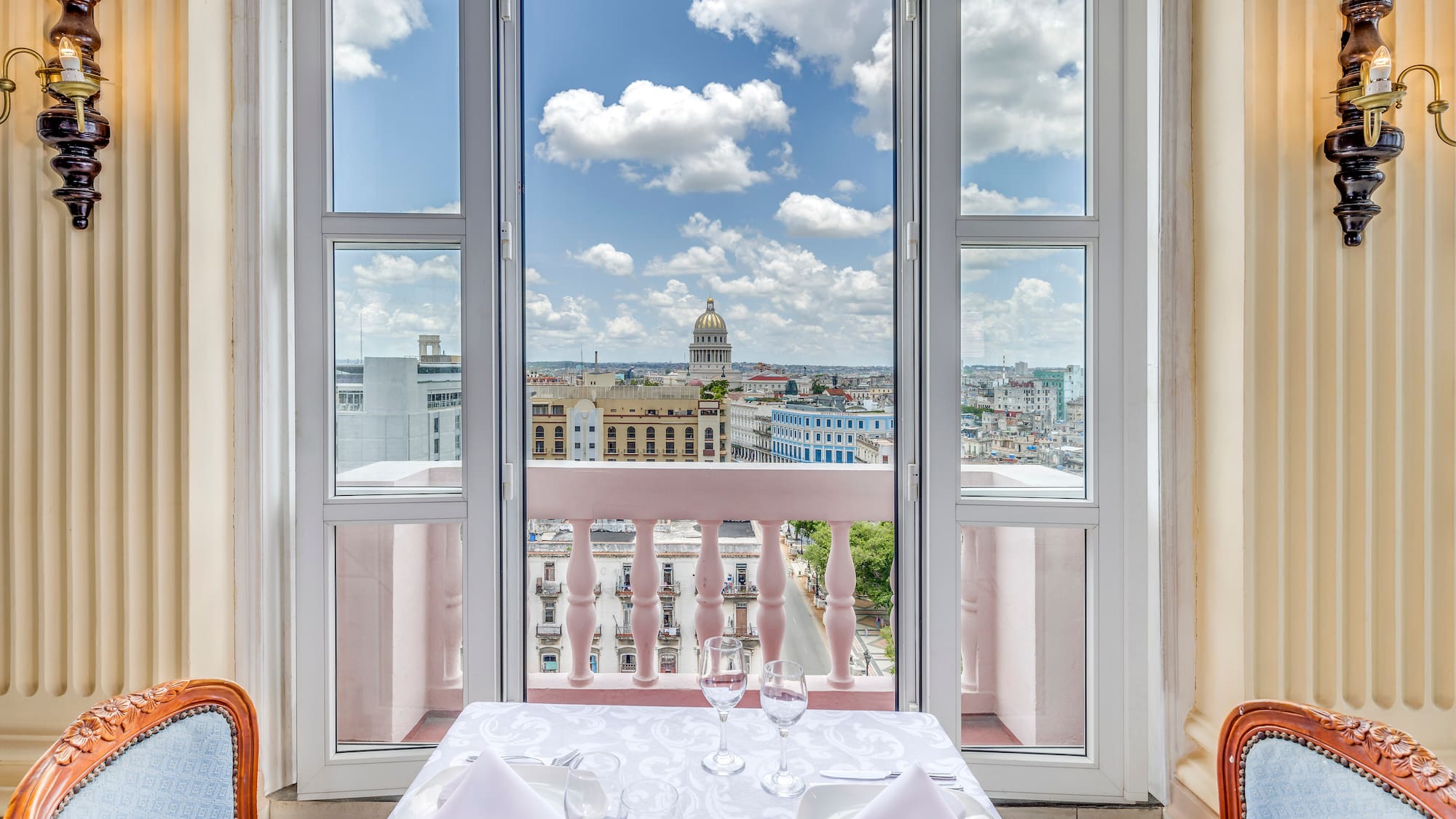 a table set for two with chairs and a balcony overlooking a city