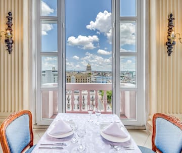 a table set for two with chairs and a balcony overlooking a city