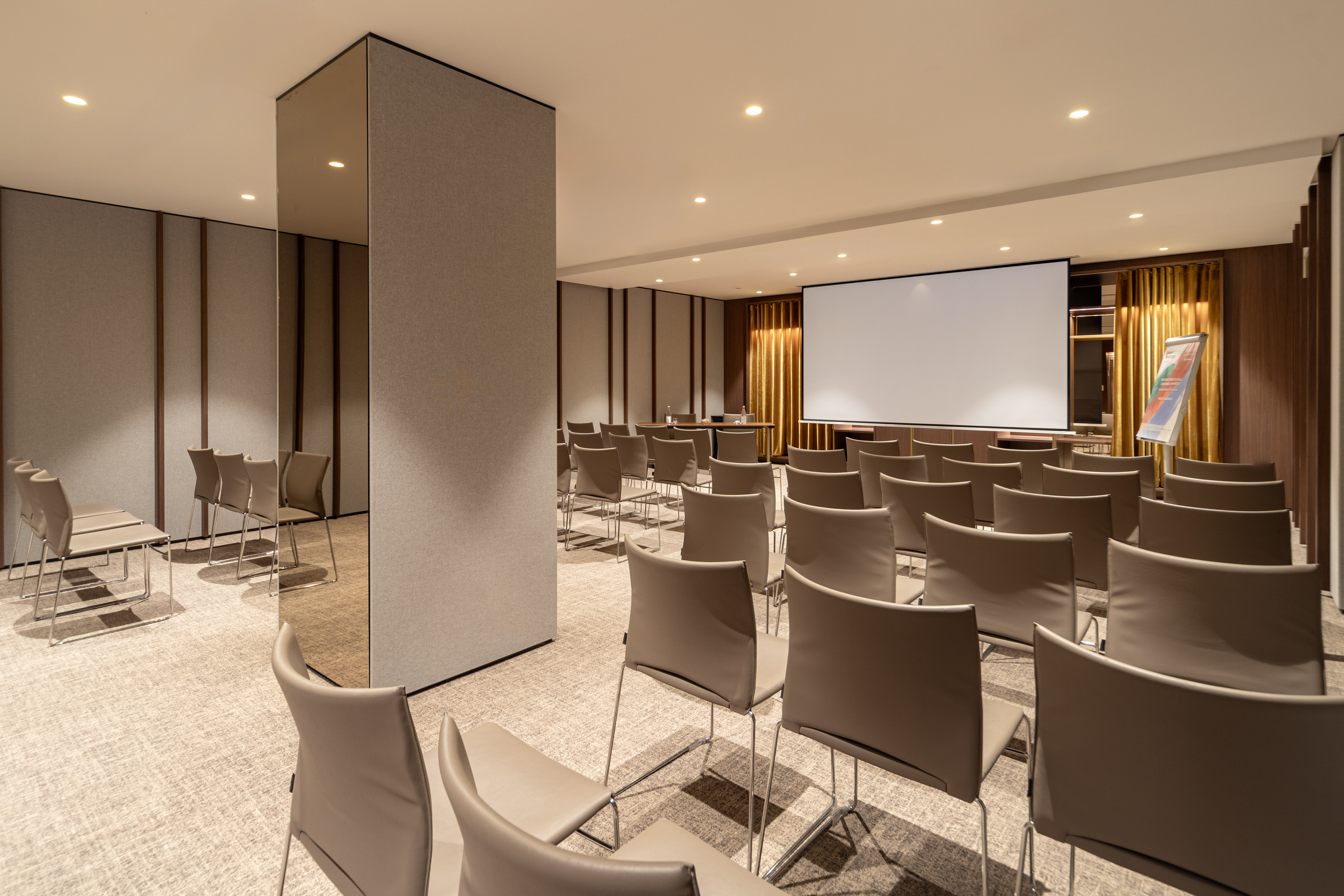 Modern conference room with rows of seating and large projector screen.