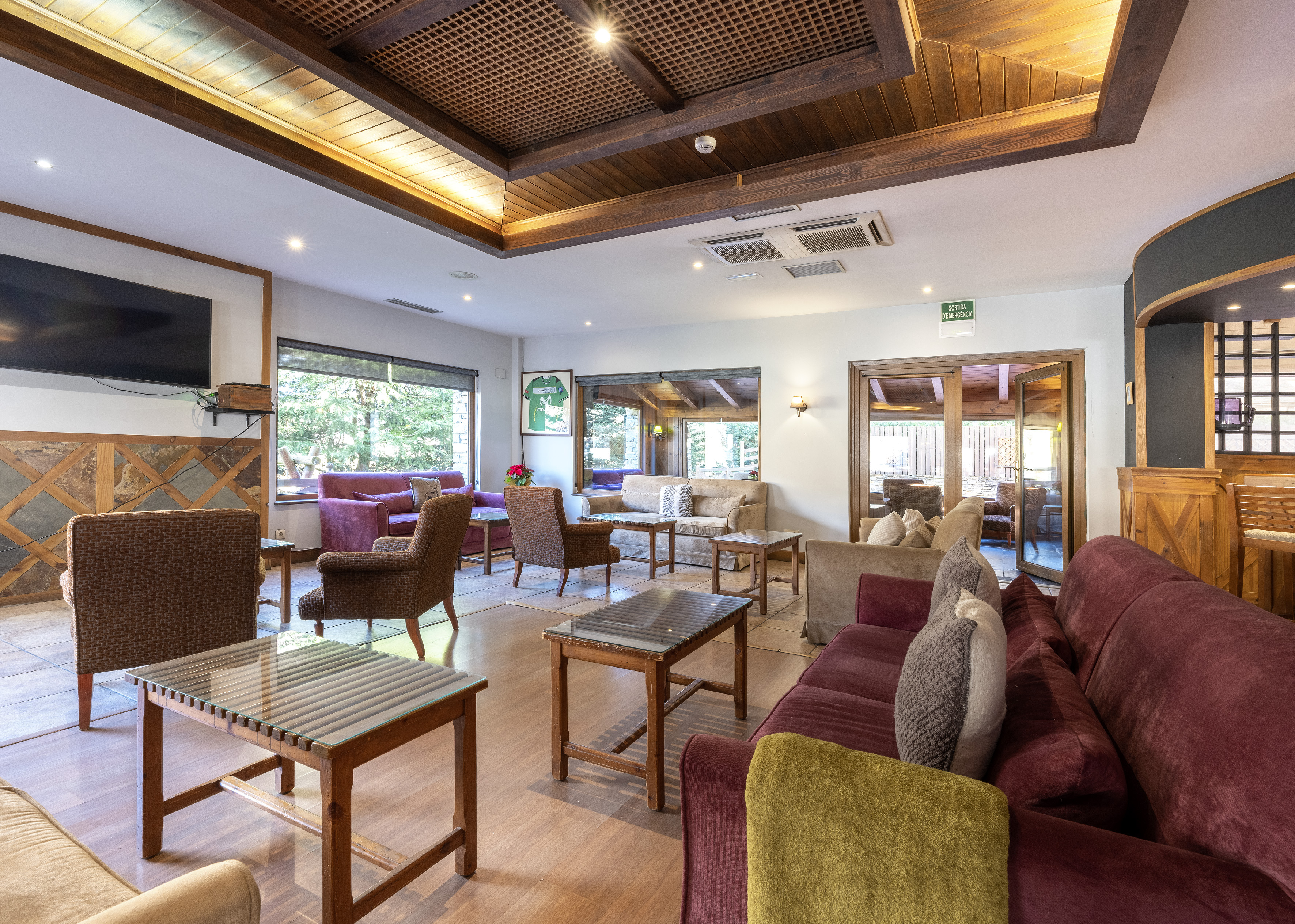 Cozy hotel lounge with comfortable sofas, wood ceiling, and large windows.