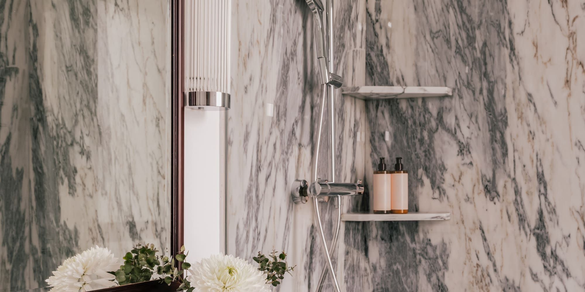 Luxury marble bathroom with vanity, ornate chrome faucet, and modern shower.