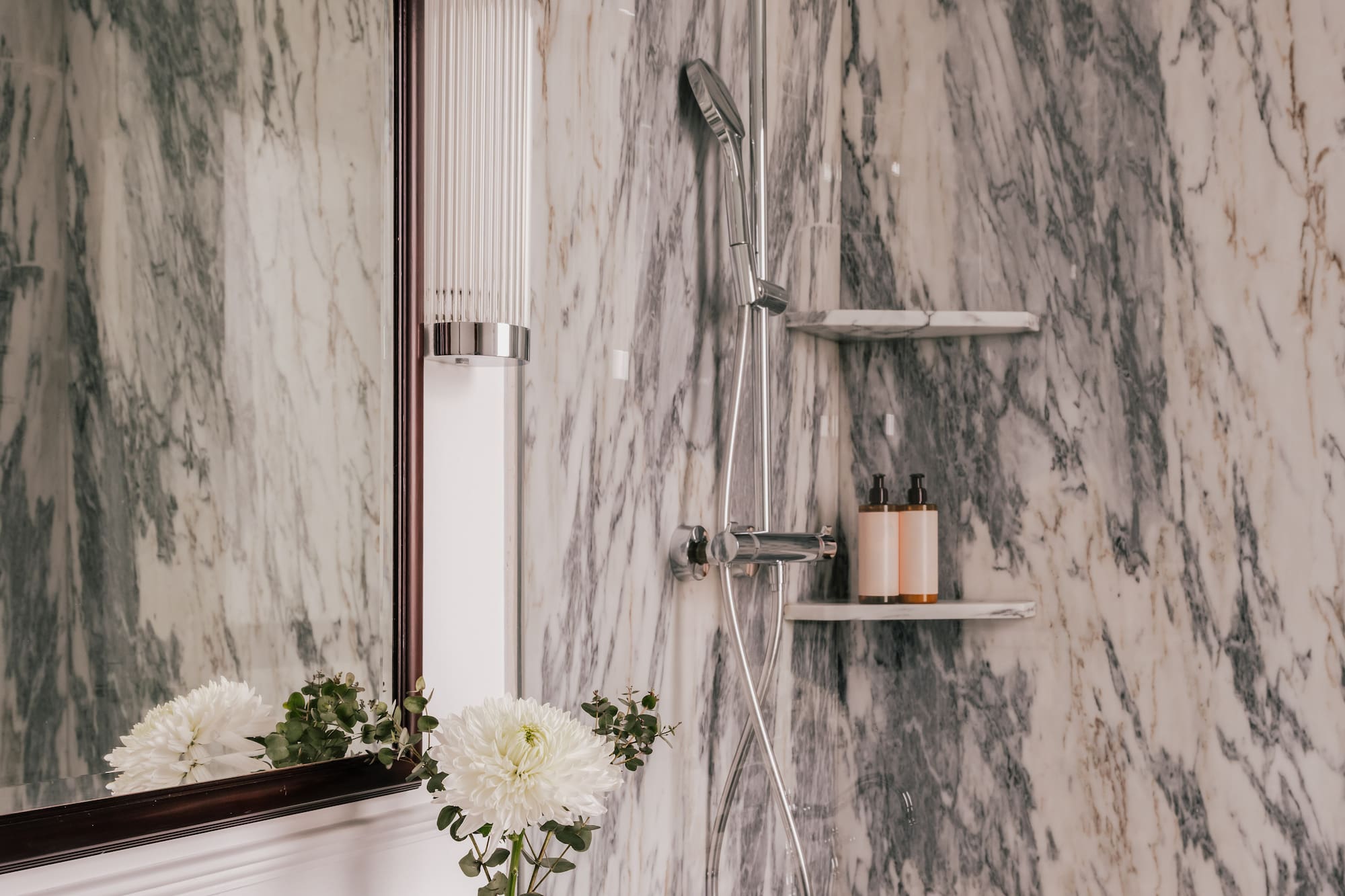 Luxury marble bathroom with vanity, ornate chrome faucet, and modern shower.