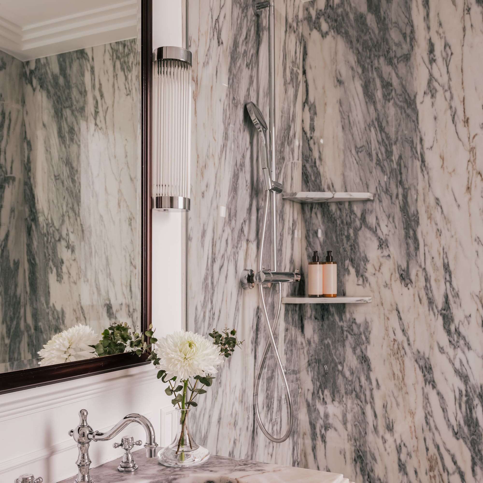 Luxury marble bathroom with vanity, ornate chrome faucet, and modern shower.
