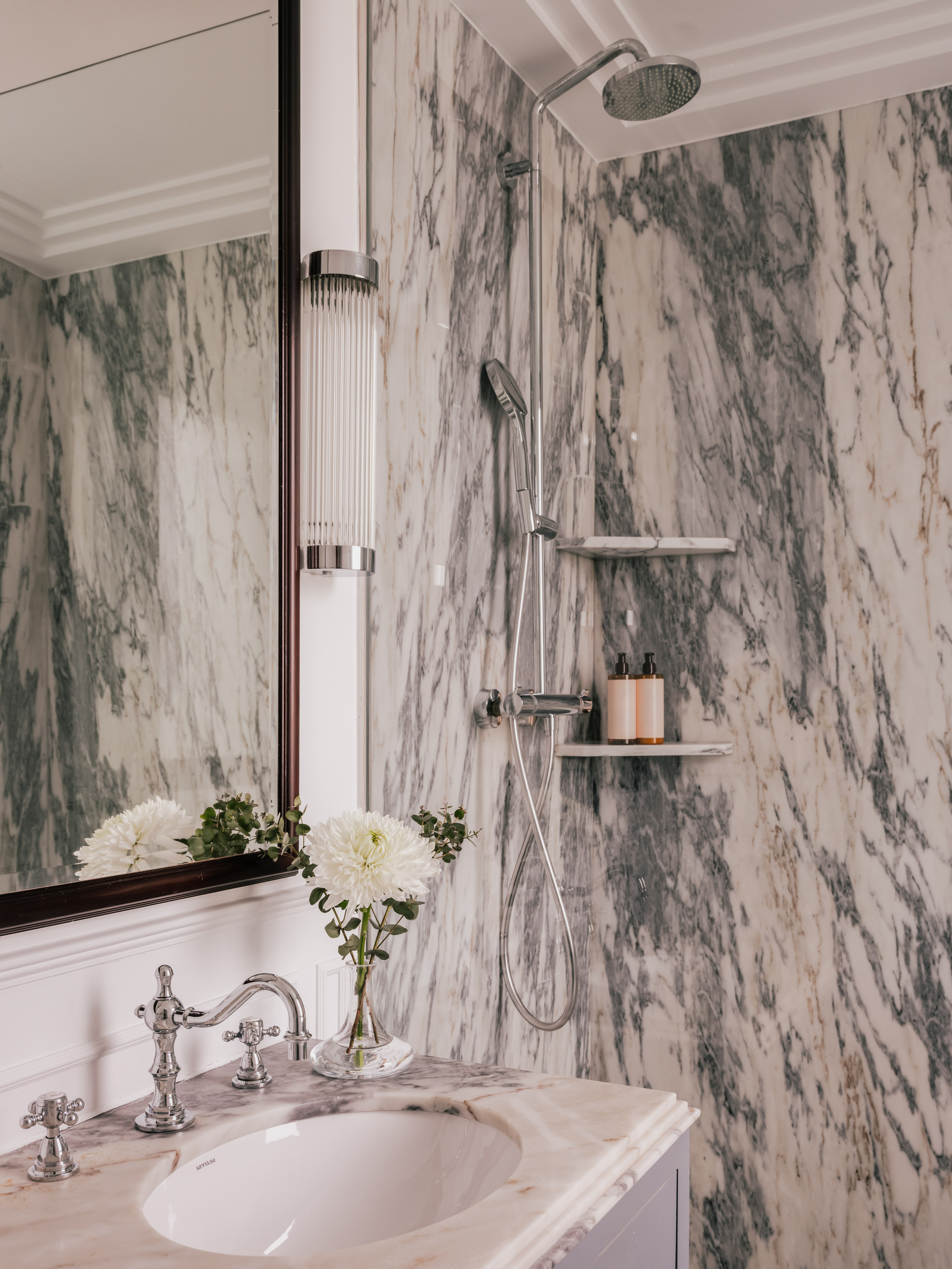 Luxury marble bathroom with vanity, ornate chrome faucet, and modern shower.
