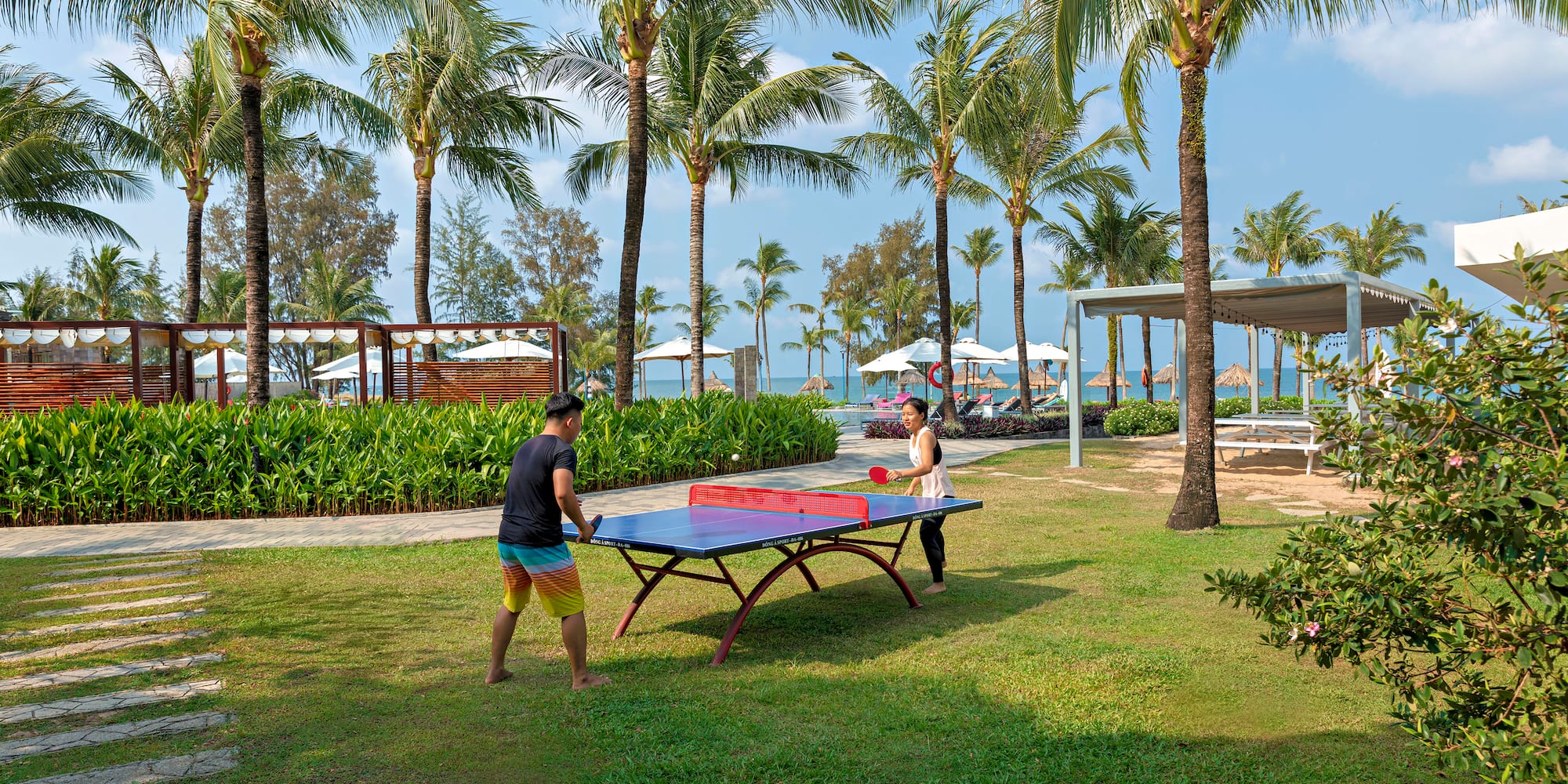 a couple of people playing ping pong outside