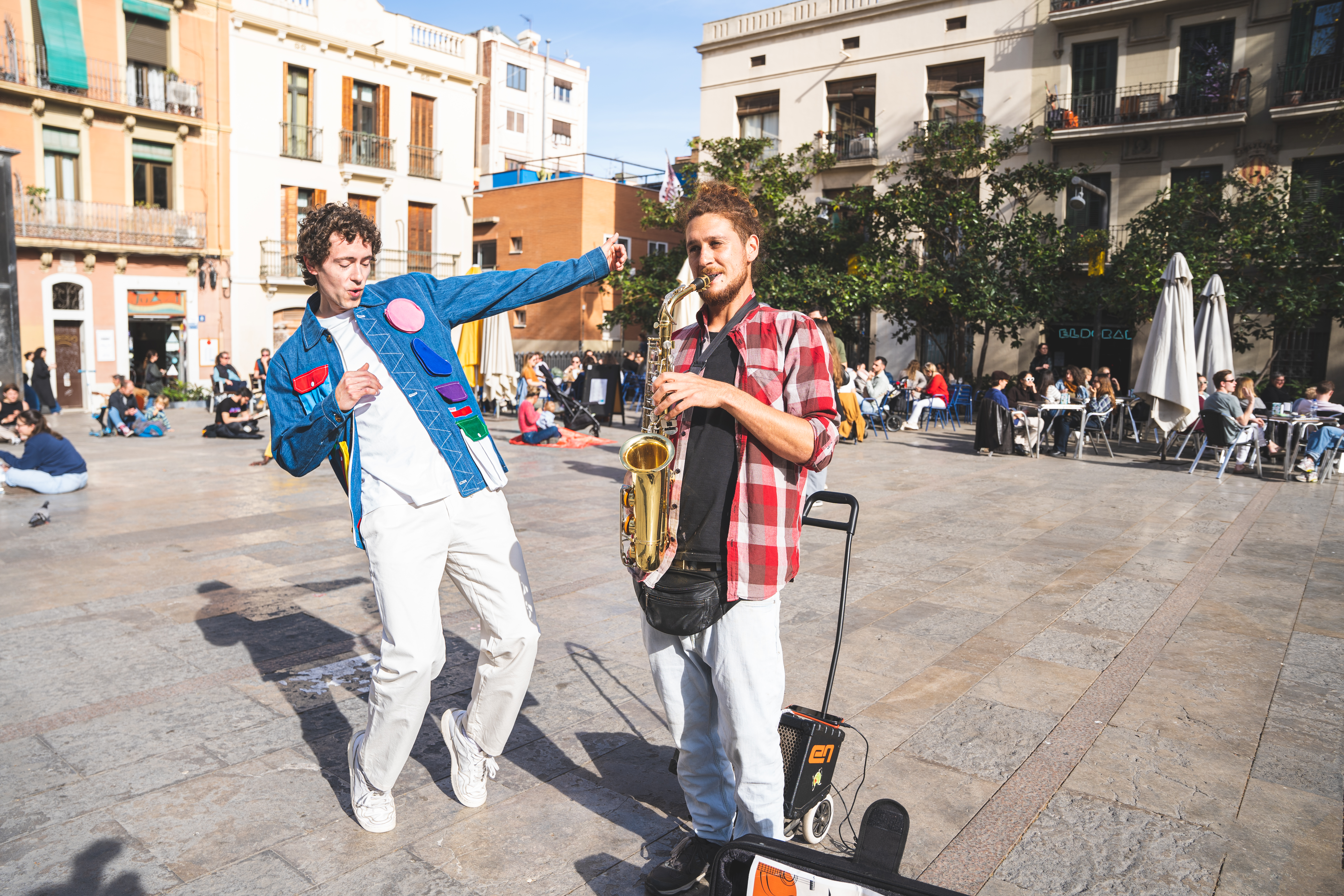 a man playing a saxophone next to a man in a blue jacket