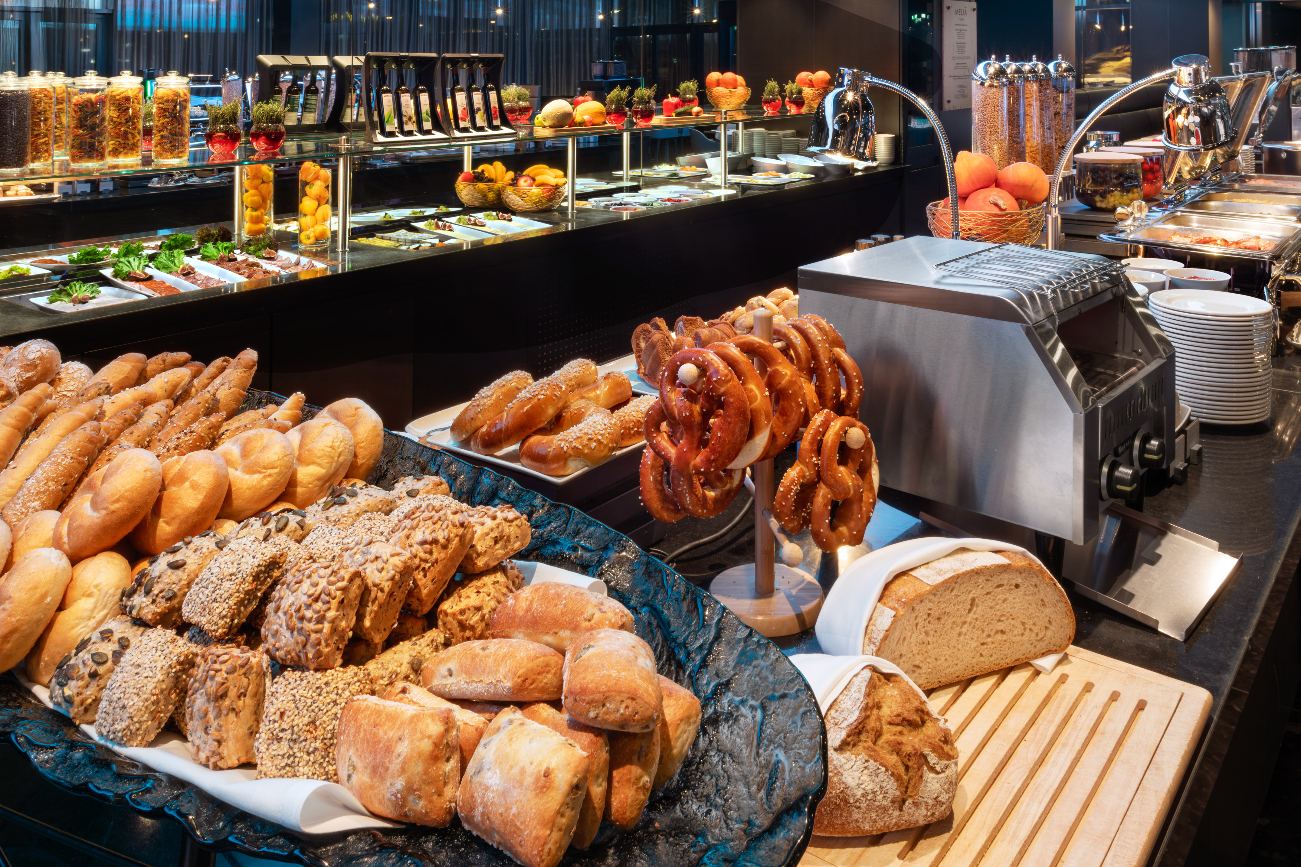 Hotel breakfast buffet with fresh bread, pretzels, pastries, and cold food options.