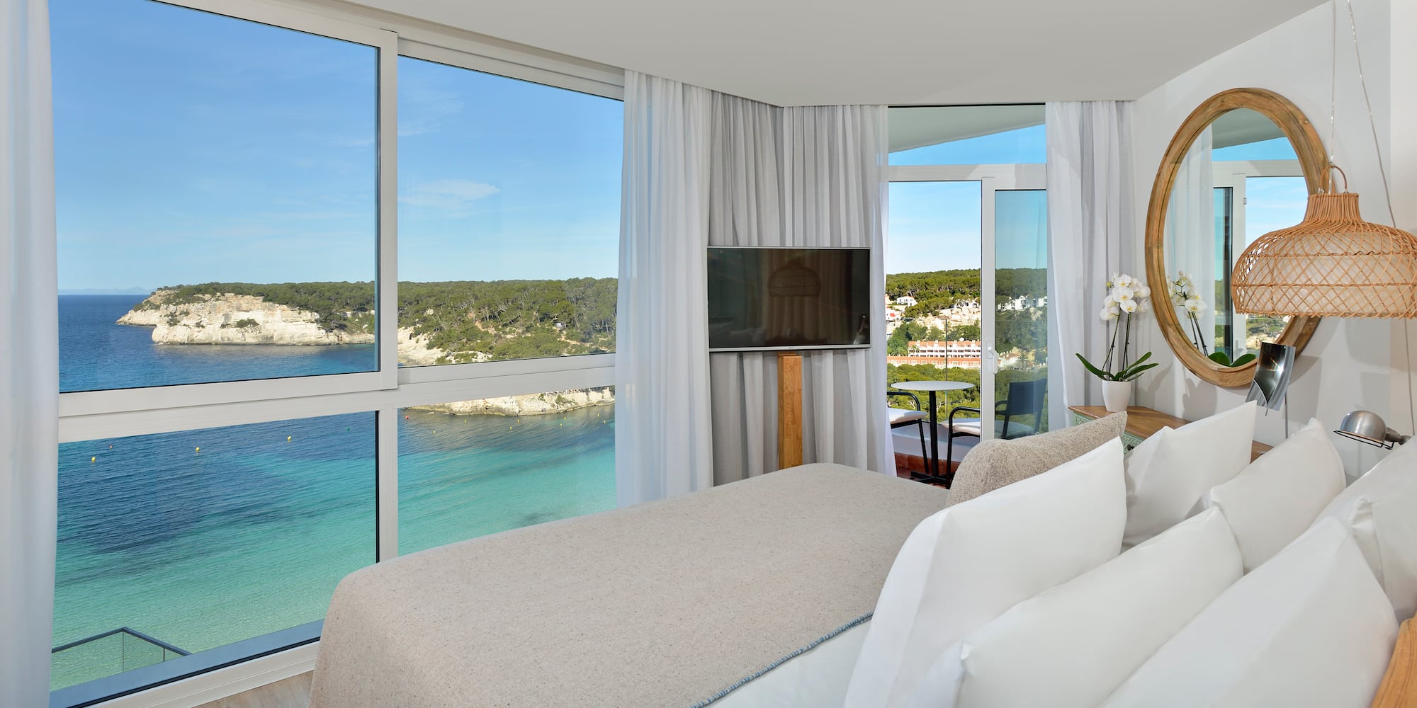 a room with a bed and a television and a view of the ocean