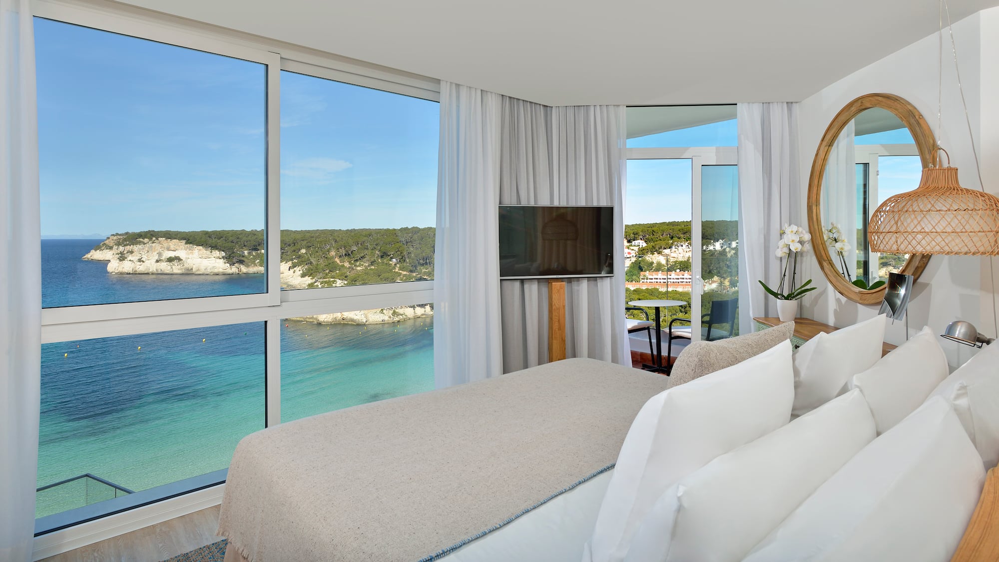 a room with a bed and a television and a view of the ocean