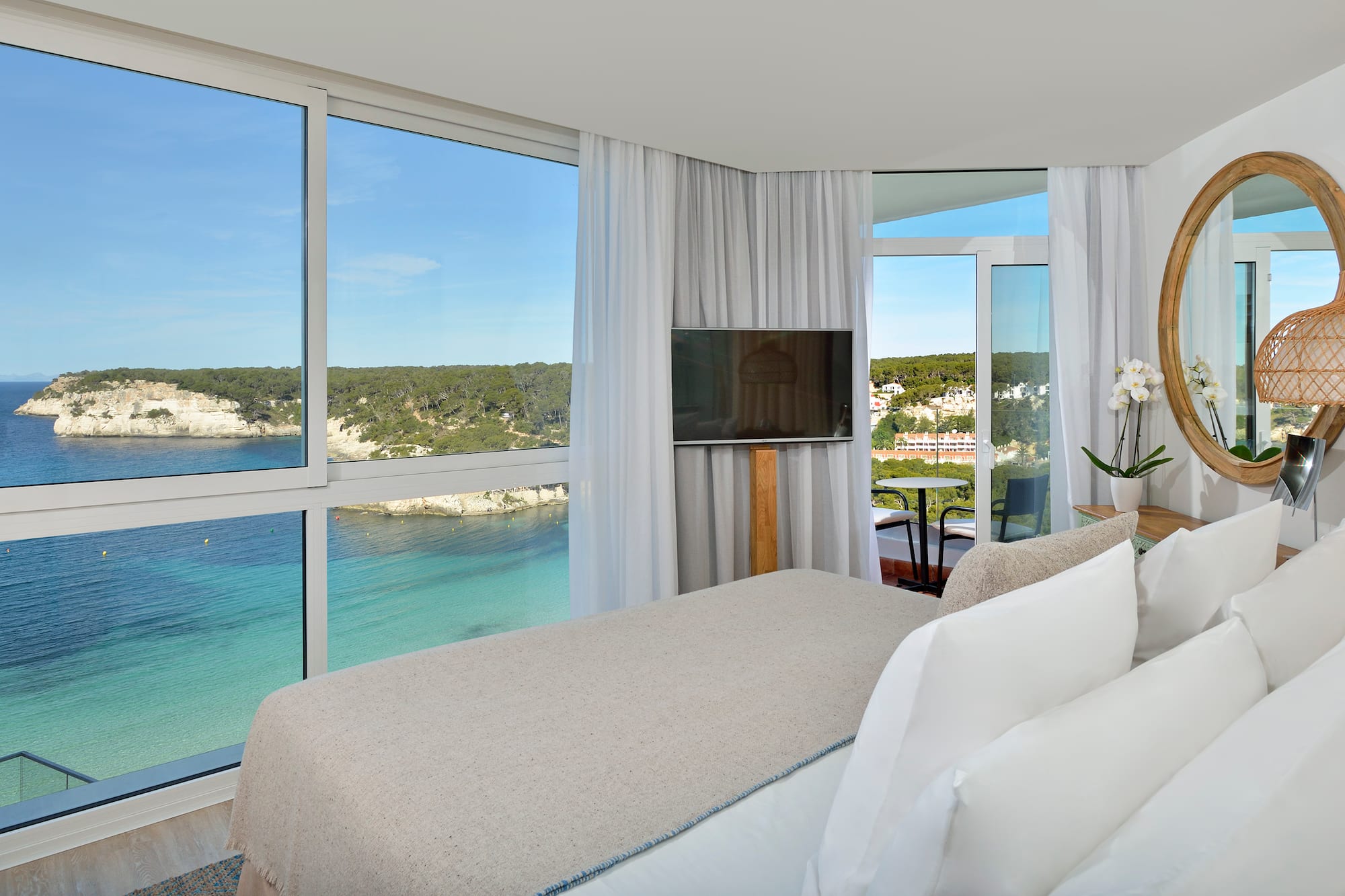 a room with a bed and a television and a view of the ocean