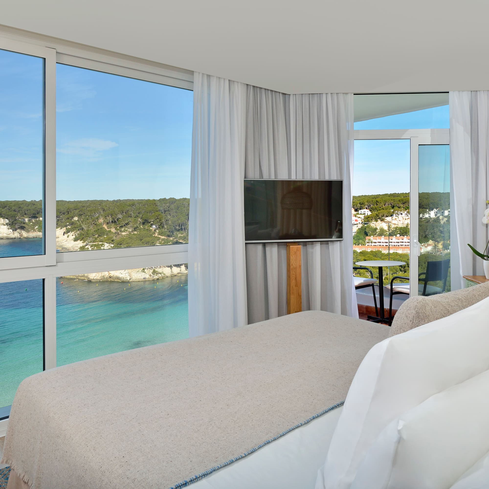 a room with a bed and a television and a view of the ocean