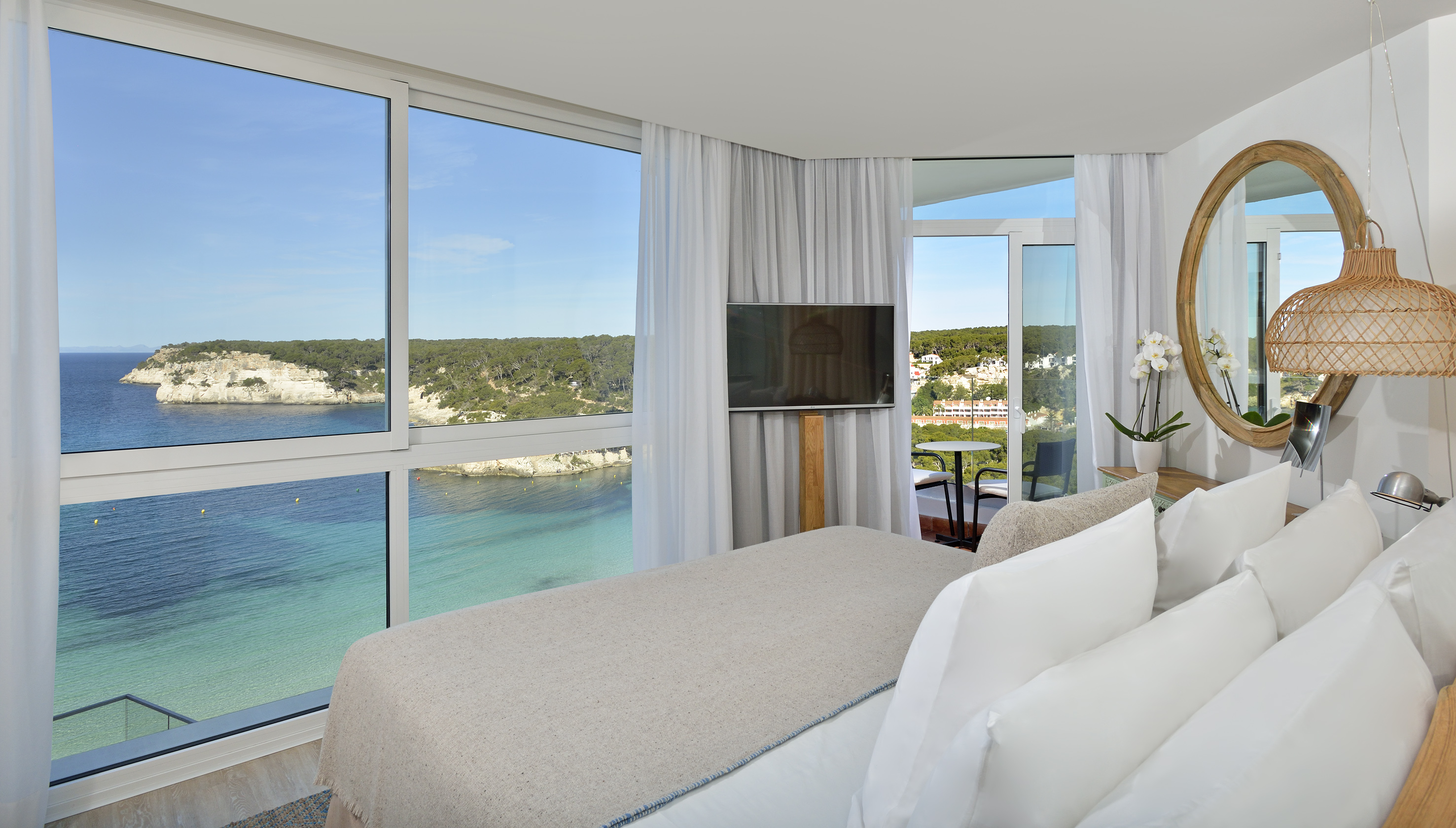 Hotel room with sea view, cliffs, and turquoise water.