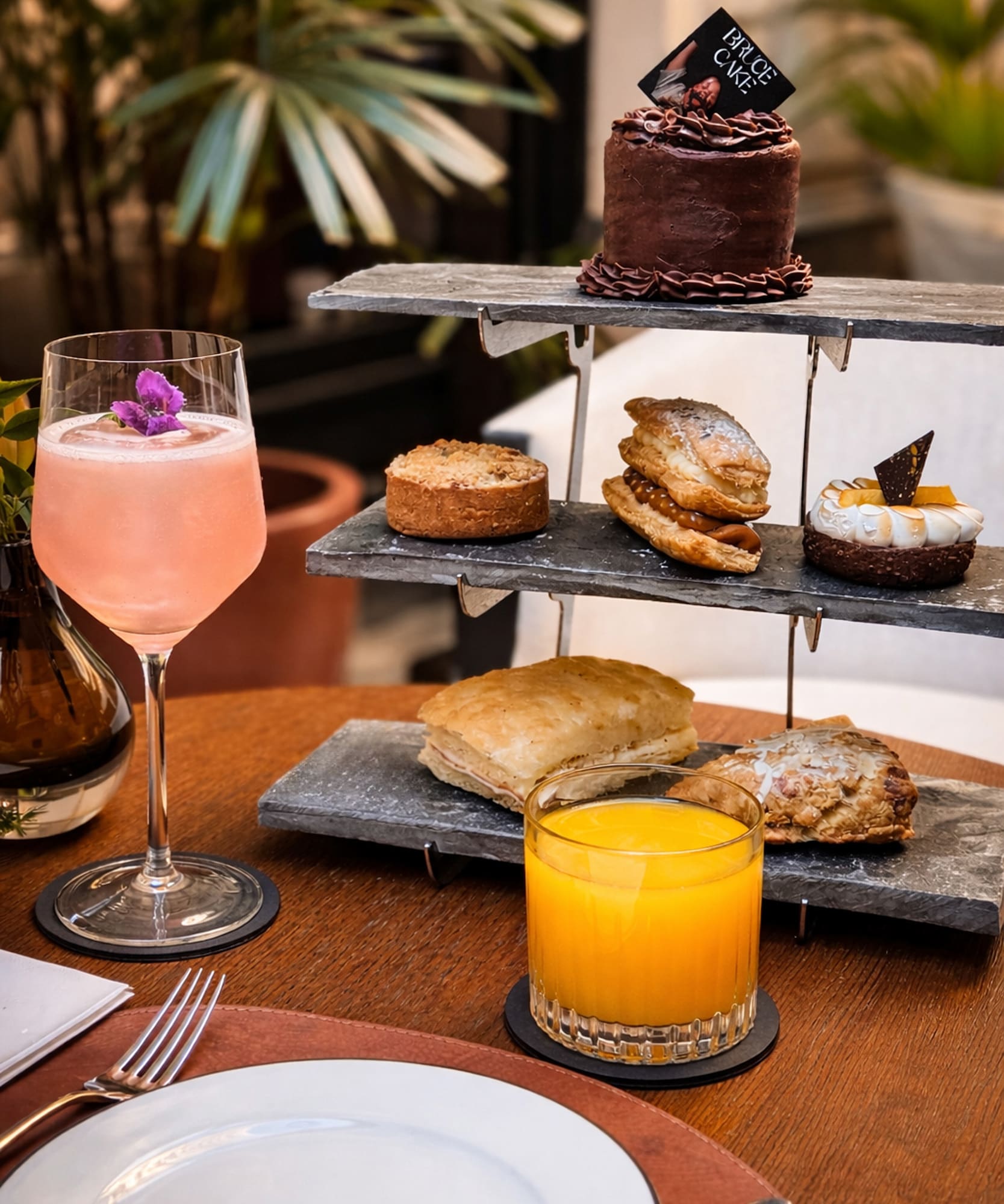 Mesa de brunch con torre de postres, pastel 'Bruce Cake', cóctel y zumo de naranja.