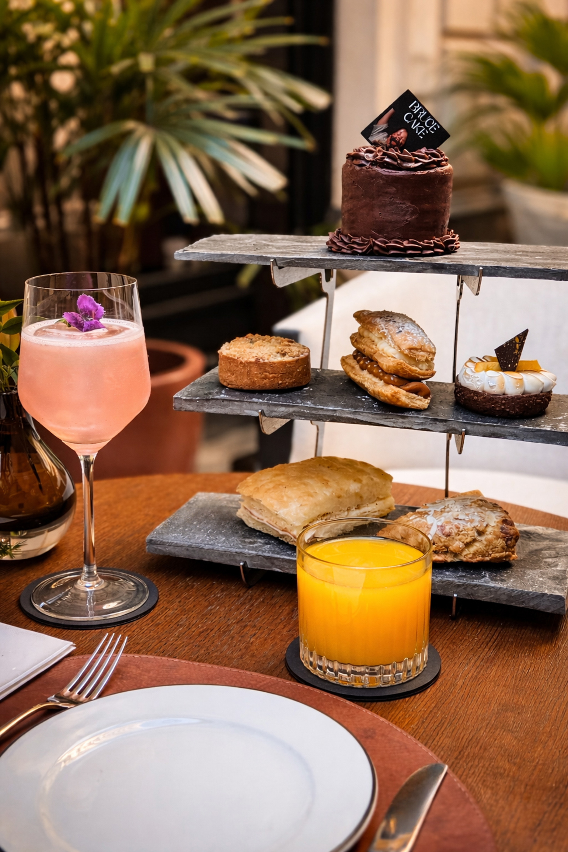 Mesa de brunch con torre de postres, pastel 'Bruce Cake', cóctel y zumo de naranja.