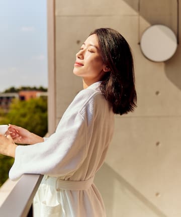 a woman in a bathrobe holding a cup