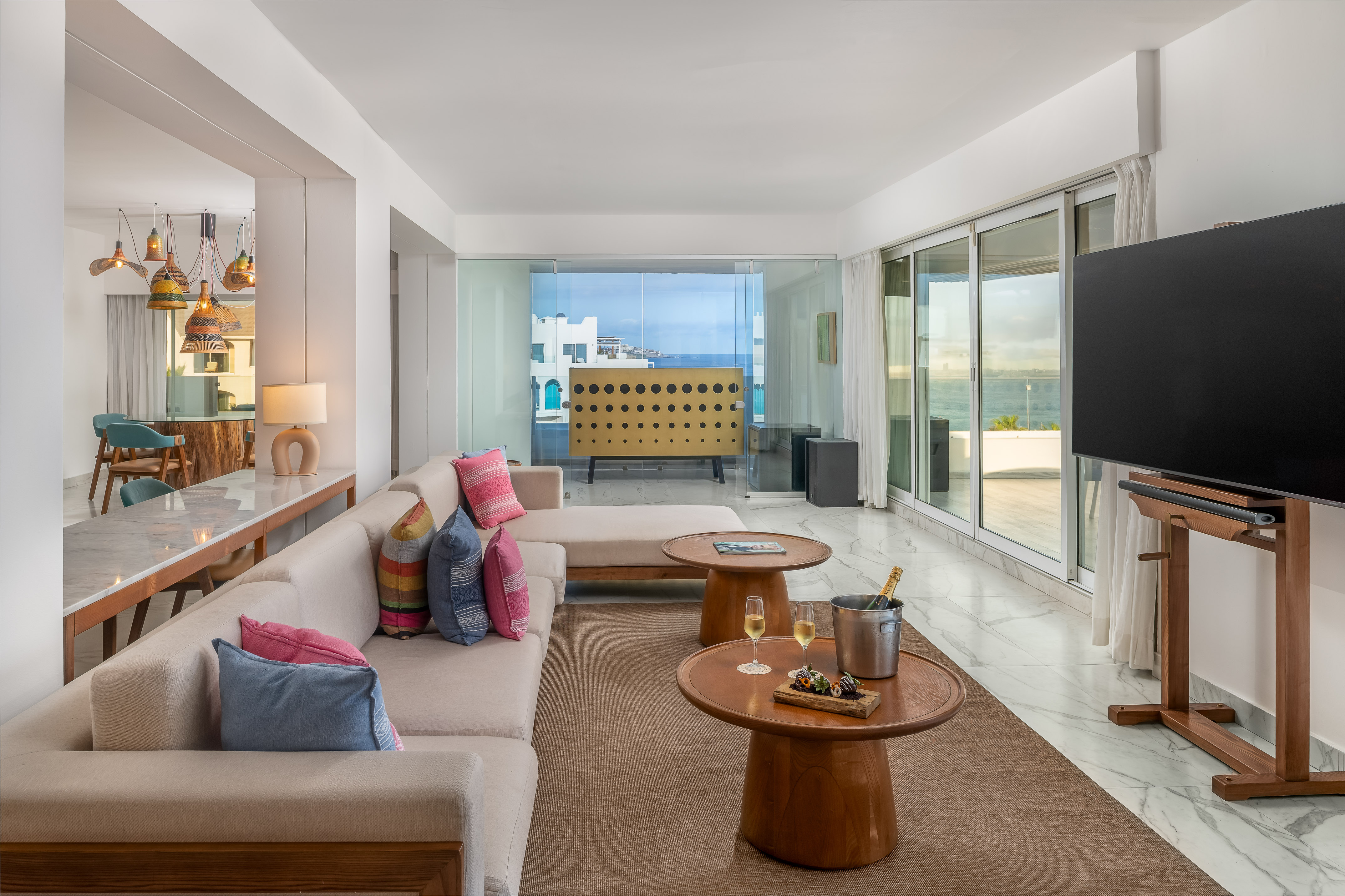 Luxury ocean view living room with modern sofa, champagne, and balcony.