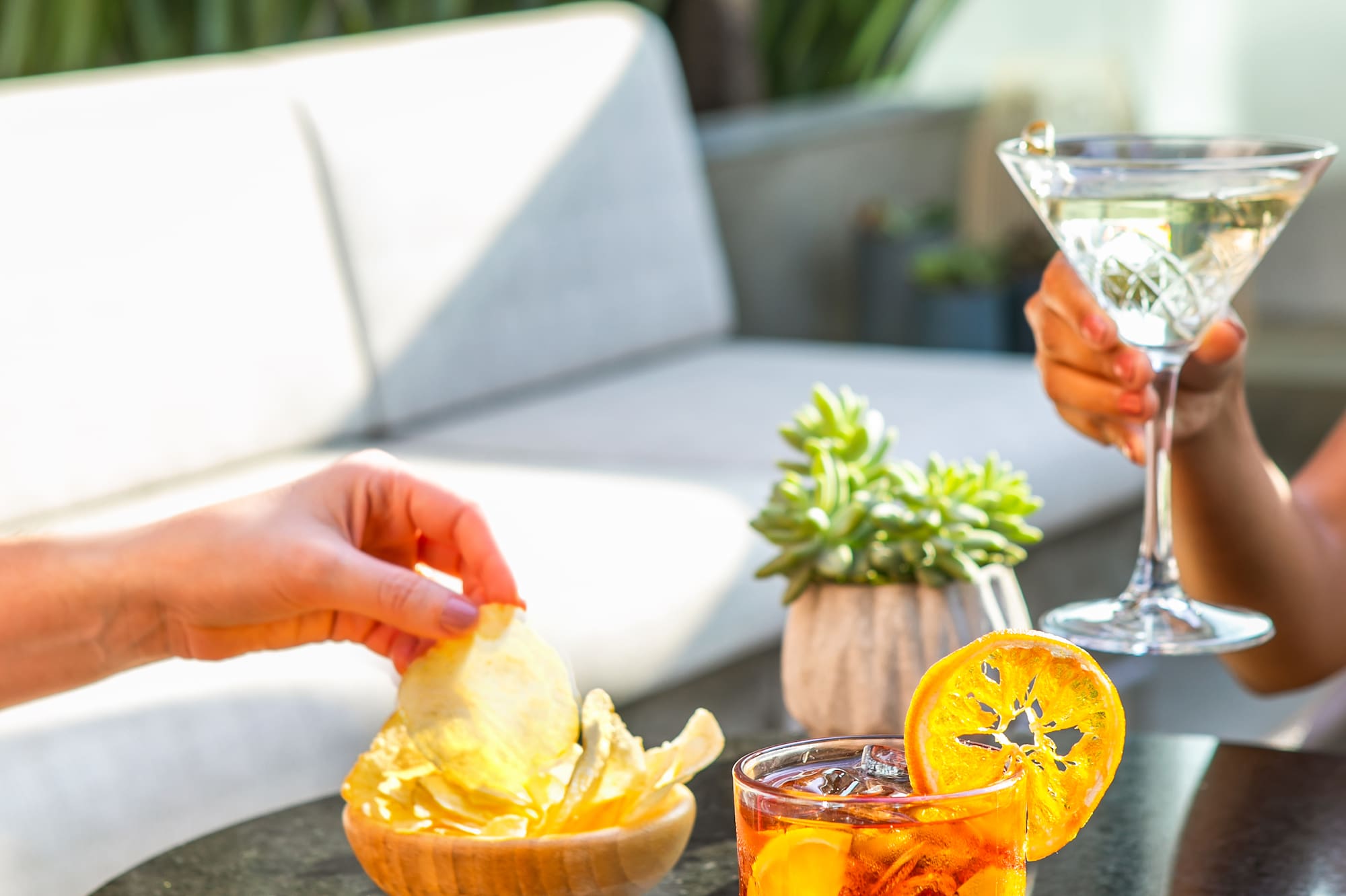 a person holding a bowl of chips and a drink on a table