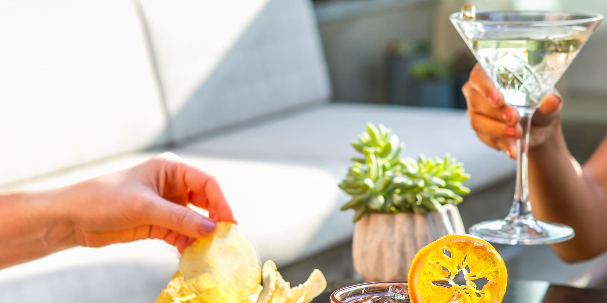 a person holding a bowl of chips and a drink on a table