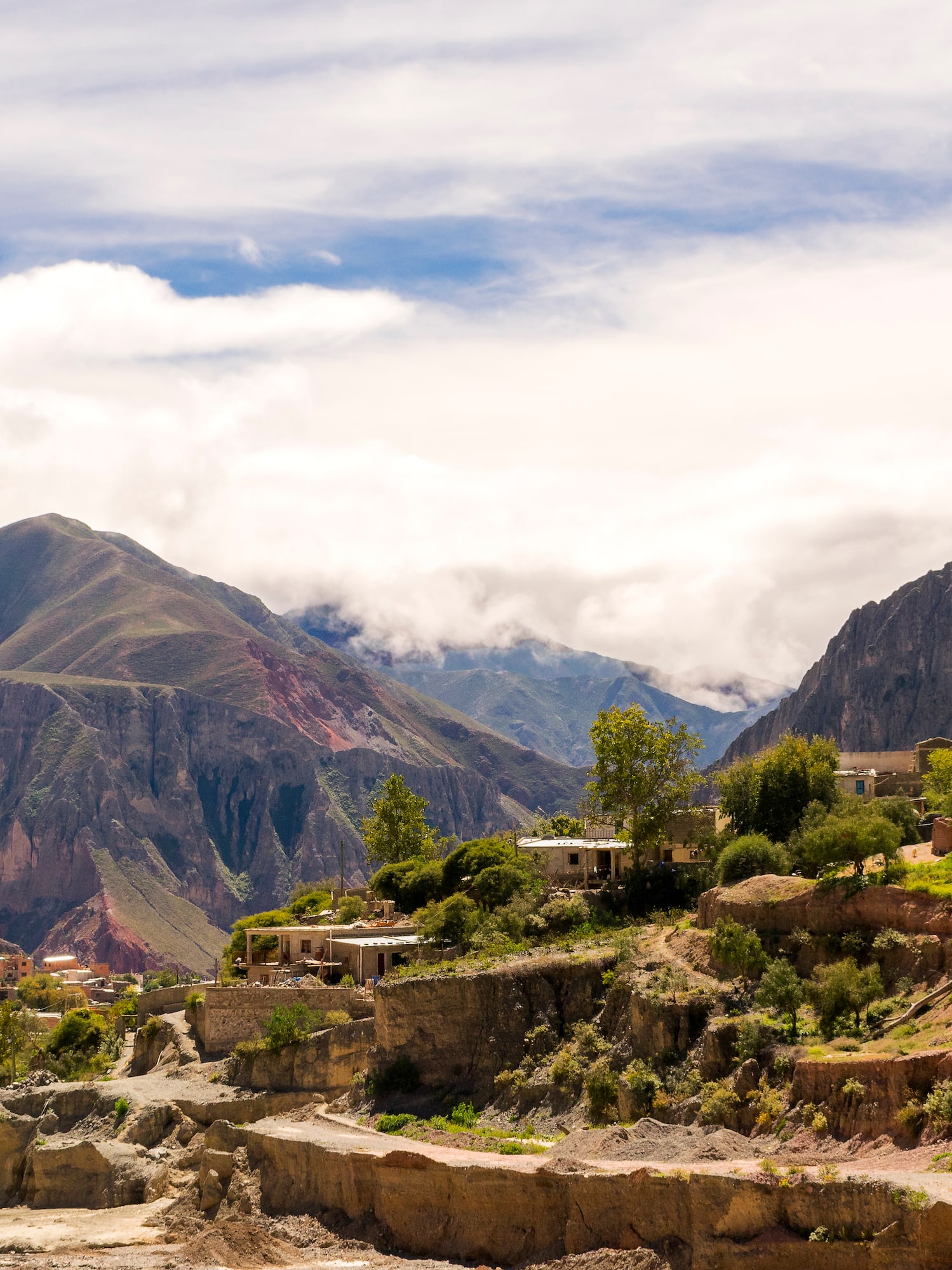 a town on a hillside with mountains in the background