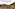 a town on a hillside with mountains in the background
