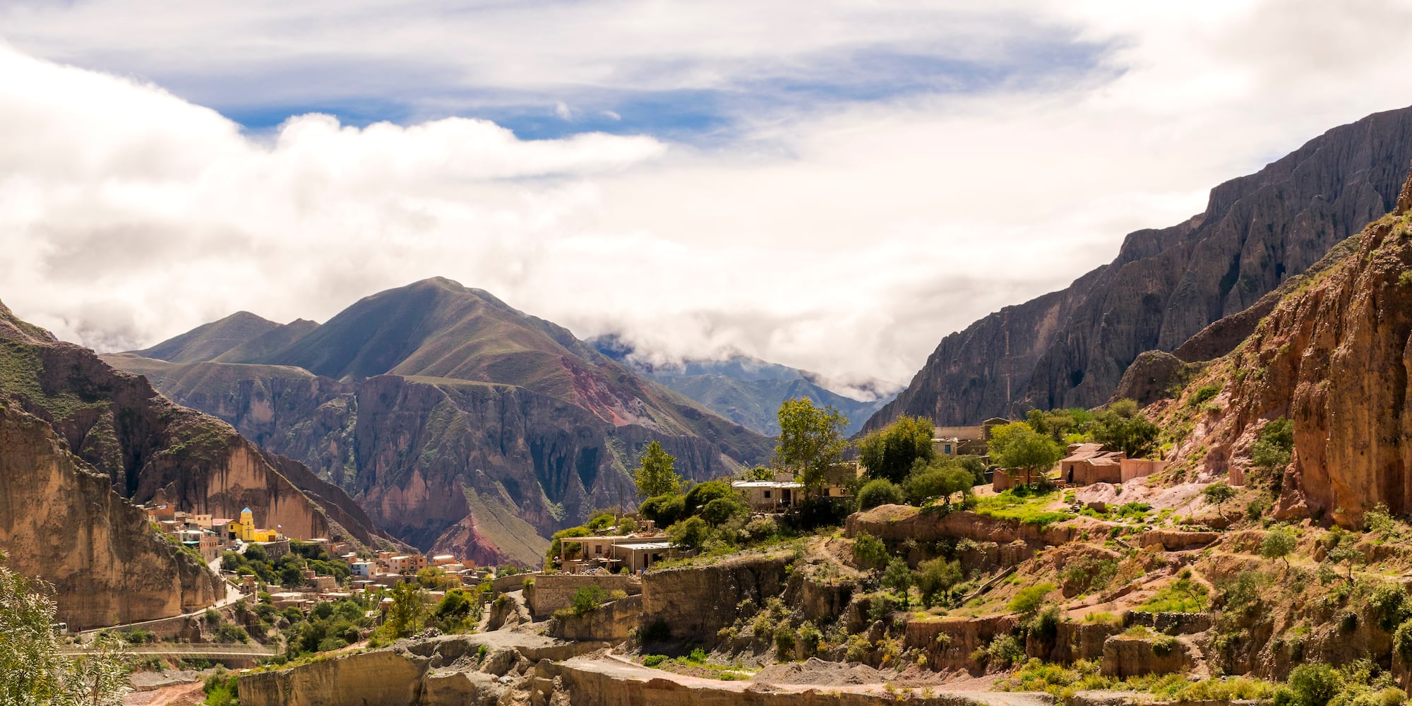 a town on a hillside with mountains in the background